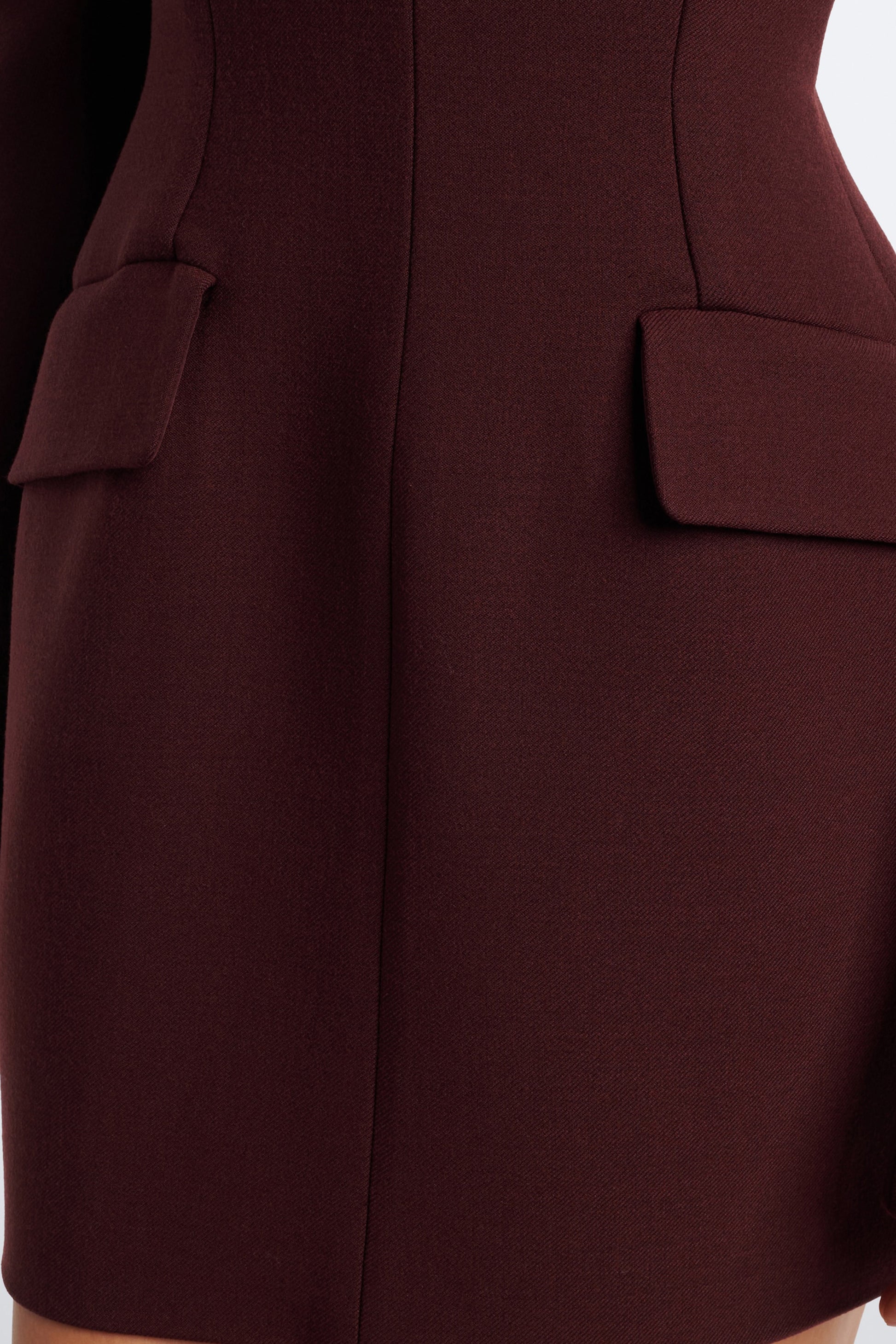 Close-up of burgundy mini dress with structured design and flap pocket details.