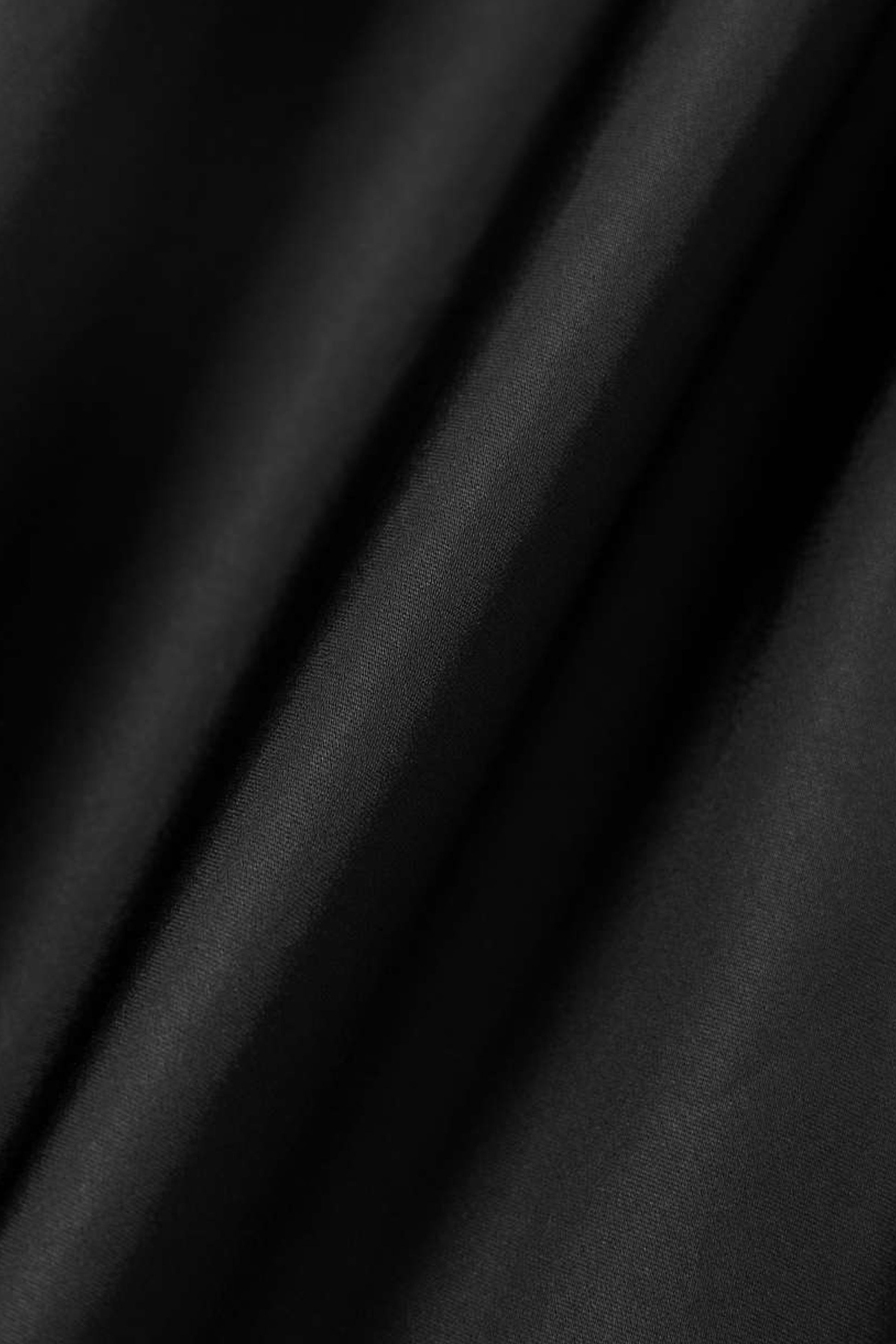 Close-up of smooth, flowing black satin fabric with subtle sheen.