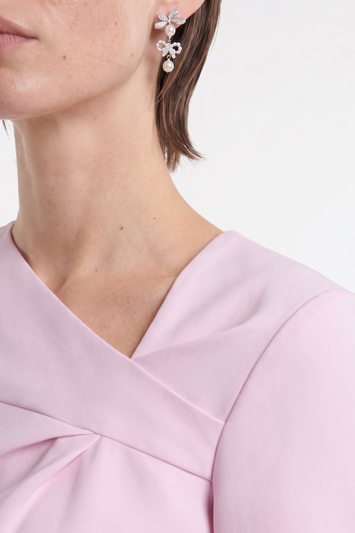 Close-up of soft pink asymmetrical dress neckline with delicate pleat detail.