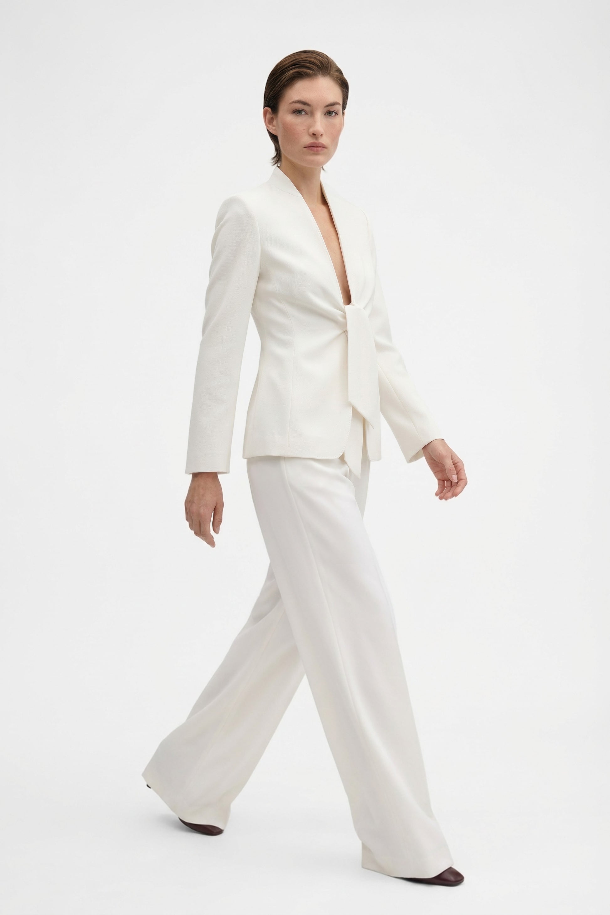 Model walking in ivory wide-leg trousers and matching blazer, front view.