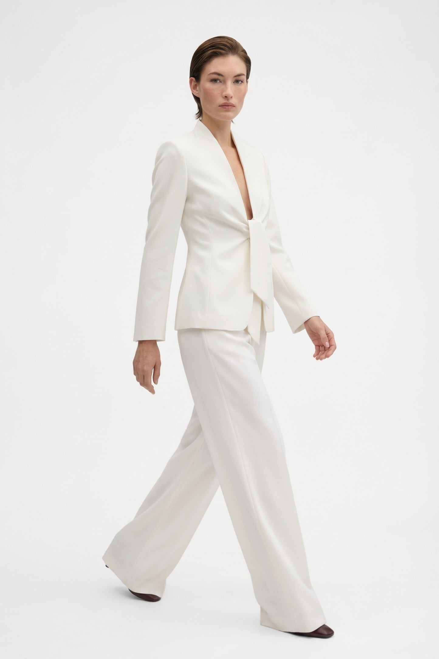 Model in ivory tie-front suit, front view, walking, elegant look, stylish ensemble.