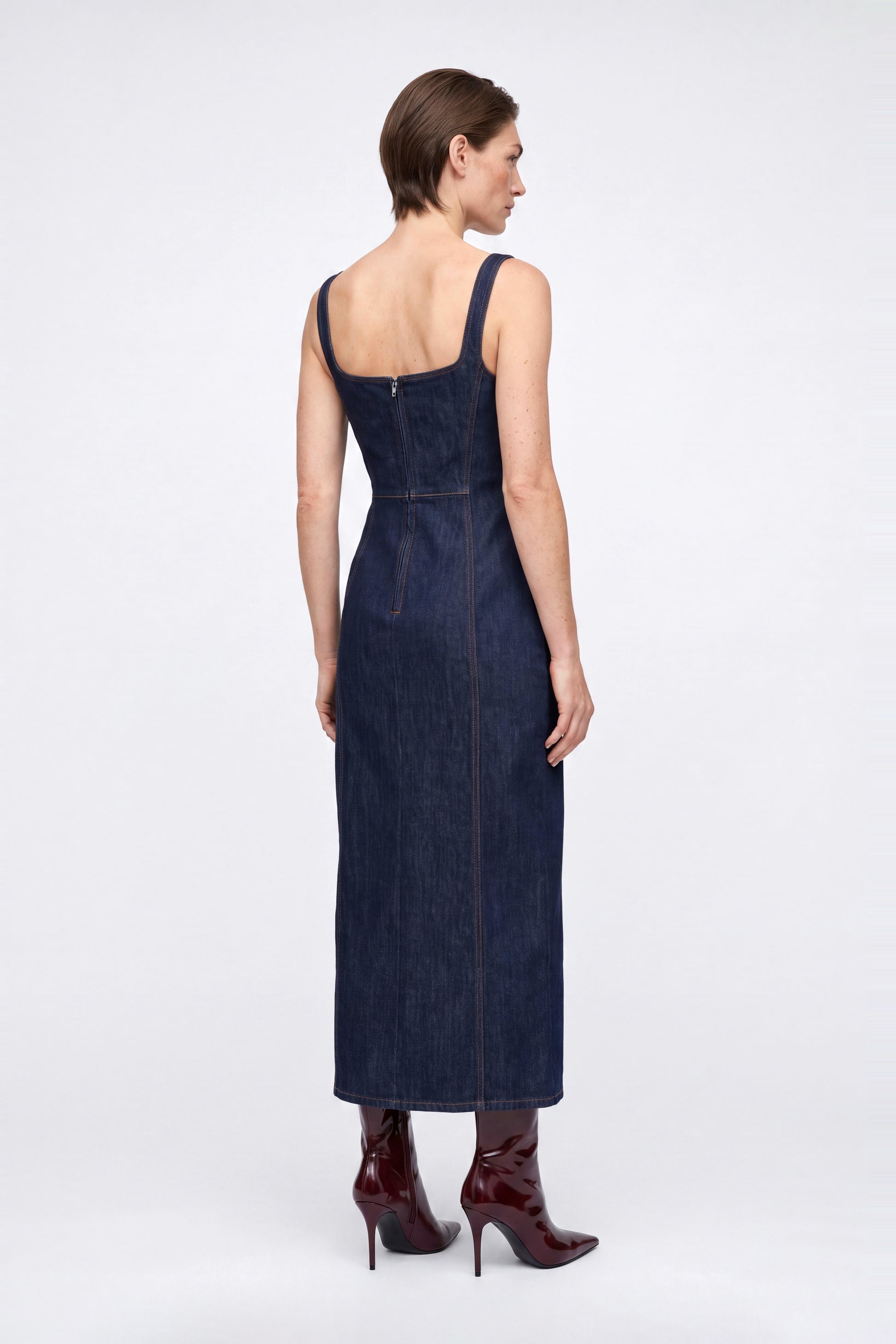 Back view of denim square neck midi dress, showing zipper and red heeled boots.
