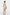Back view of model wearing cream dress with ruffle shoulder, holding clutch.