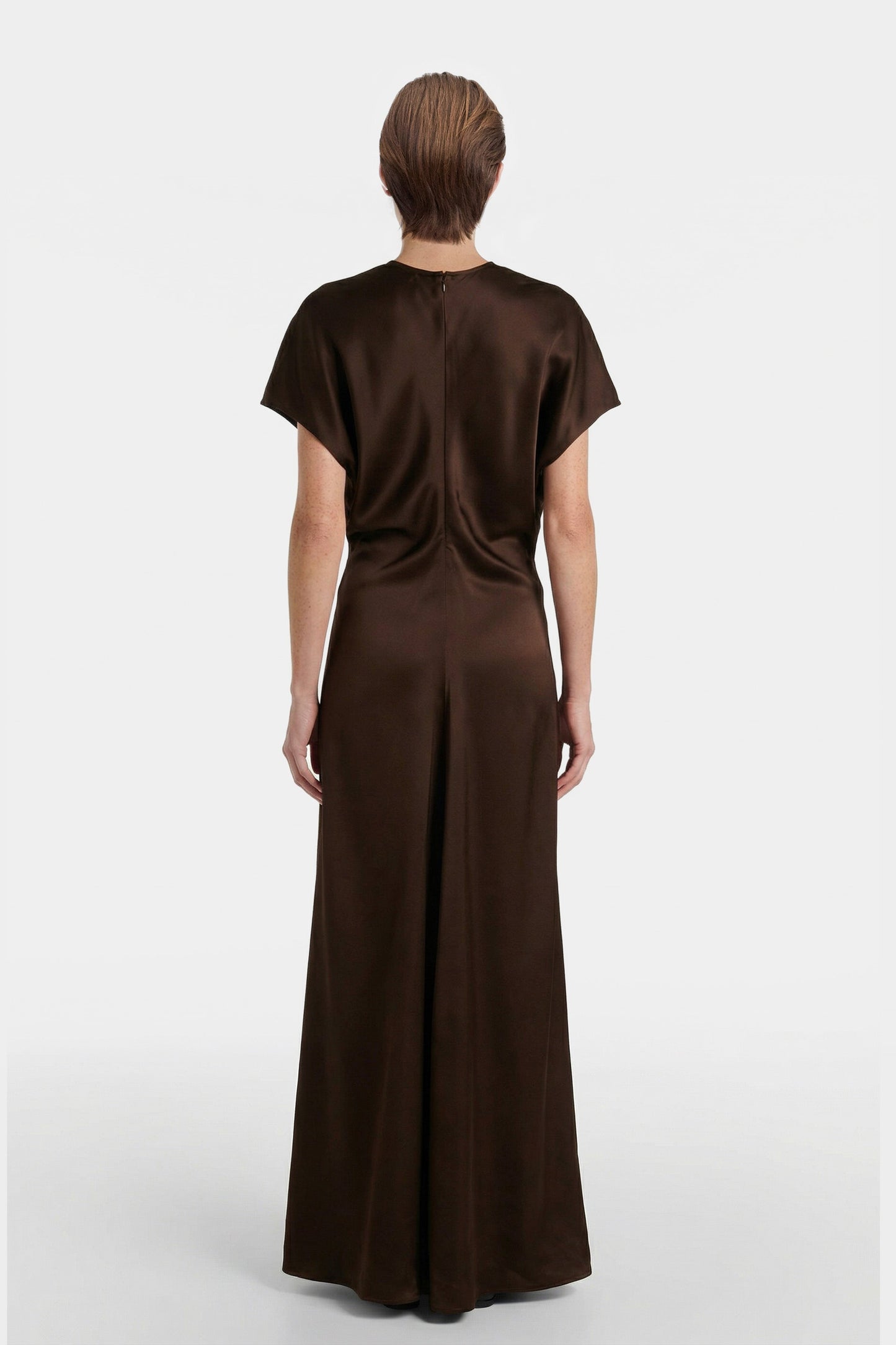 Back view of chocolate satin maxi dress with short sleeves, worn by model.