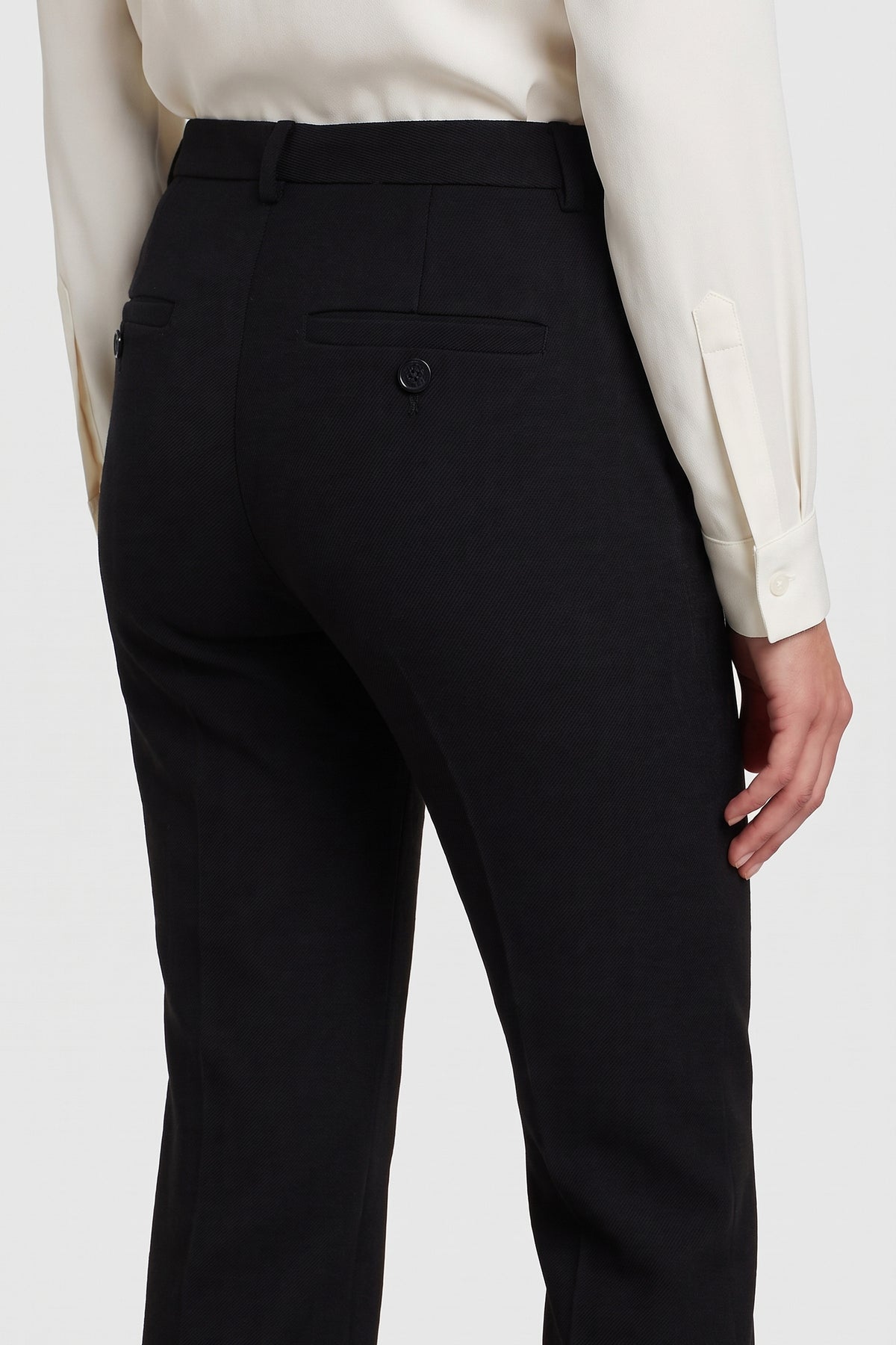Back view of tailored black suit pants, showing rear pocket details and white shirt.