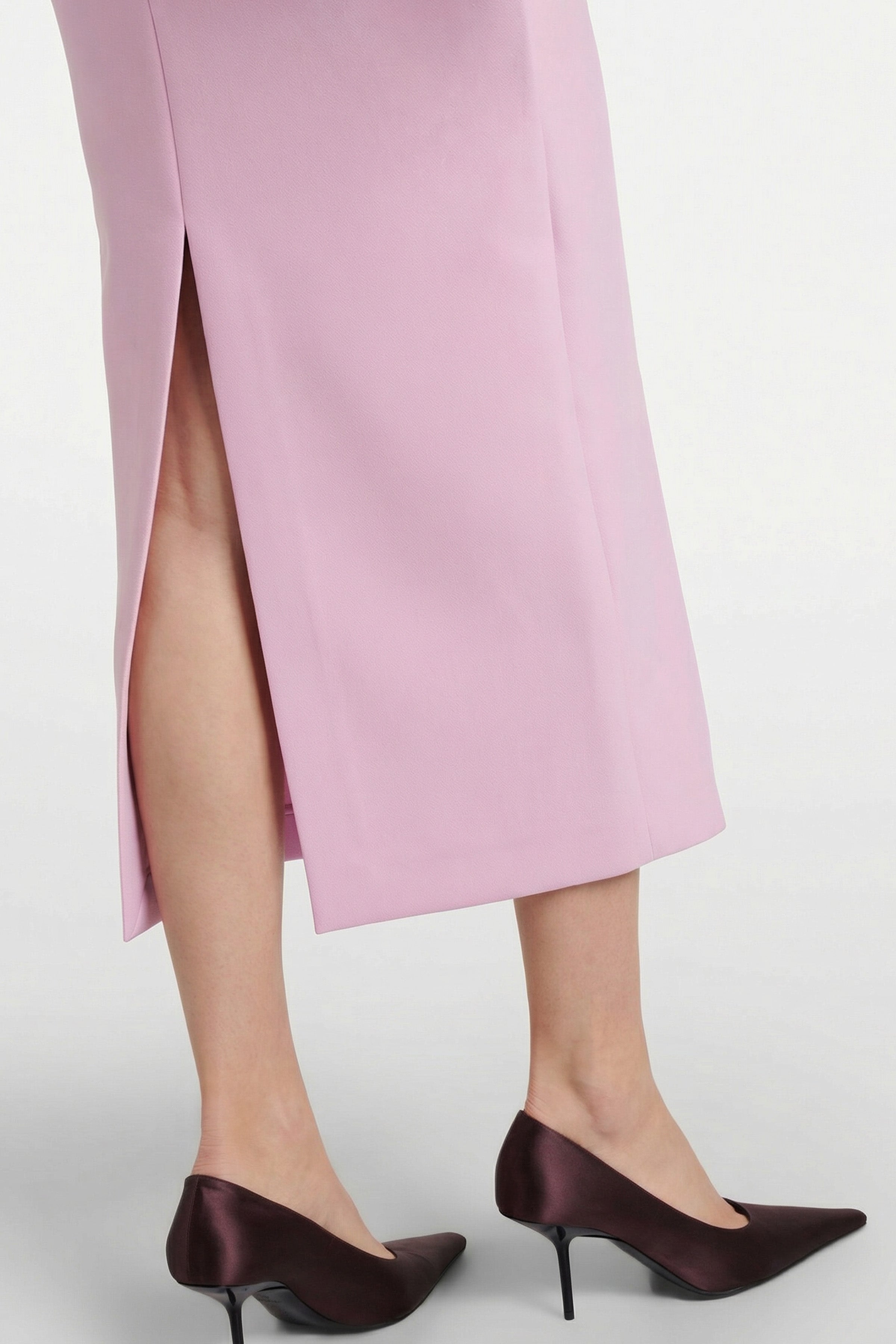 Close-up of back slit in Blush Elegance Midi Dress, model wearing black heels.