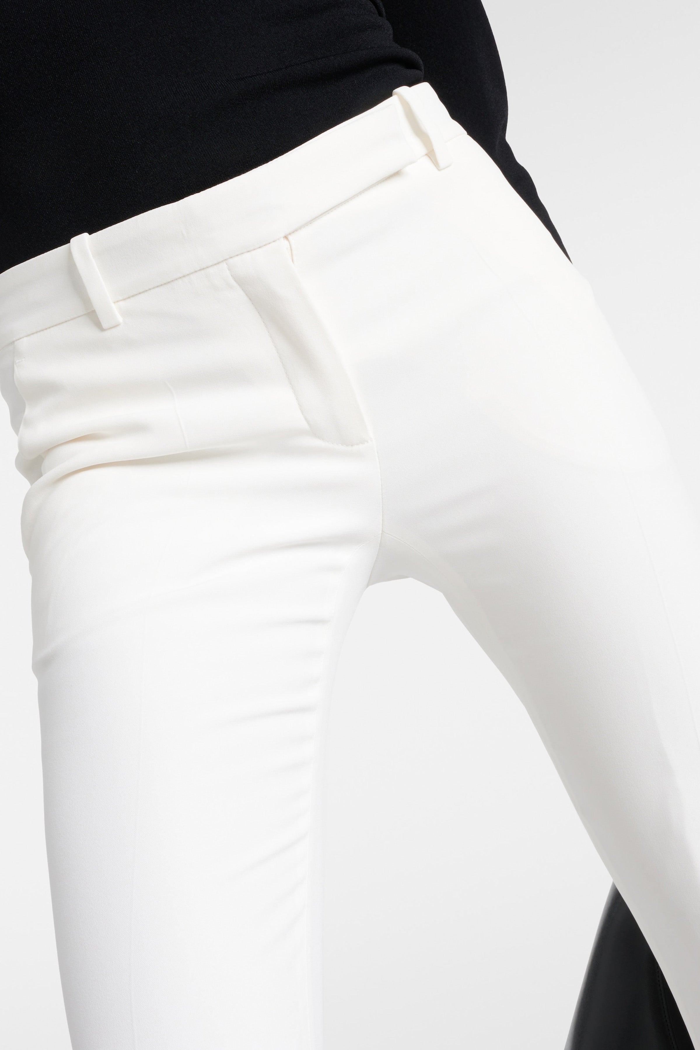 Close-up front view of ivory tailored flare pants, highlighting sleek fit and waist details.