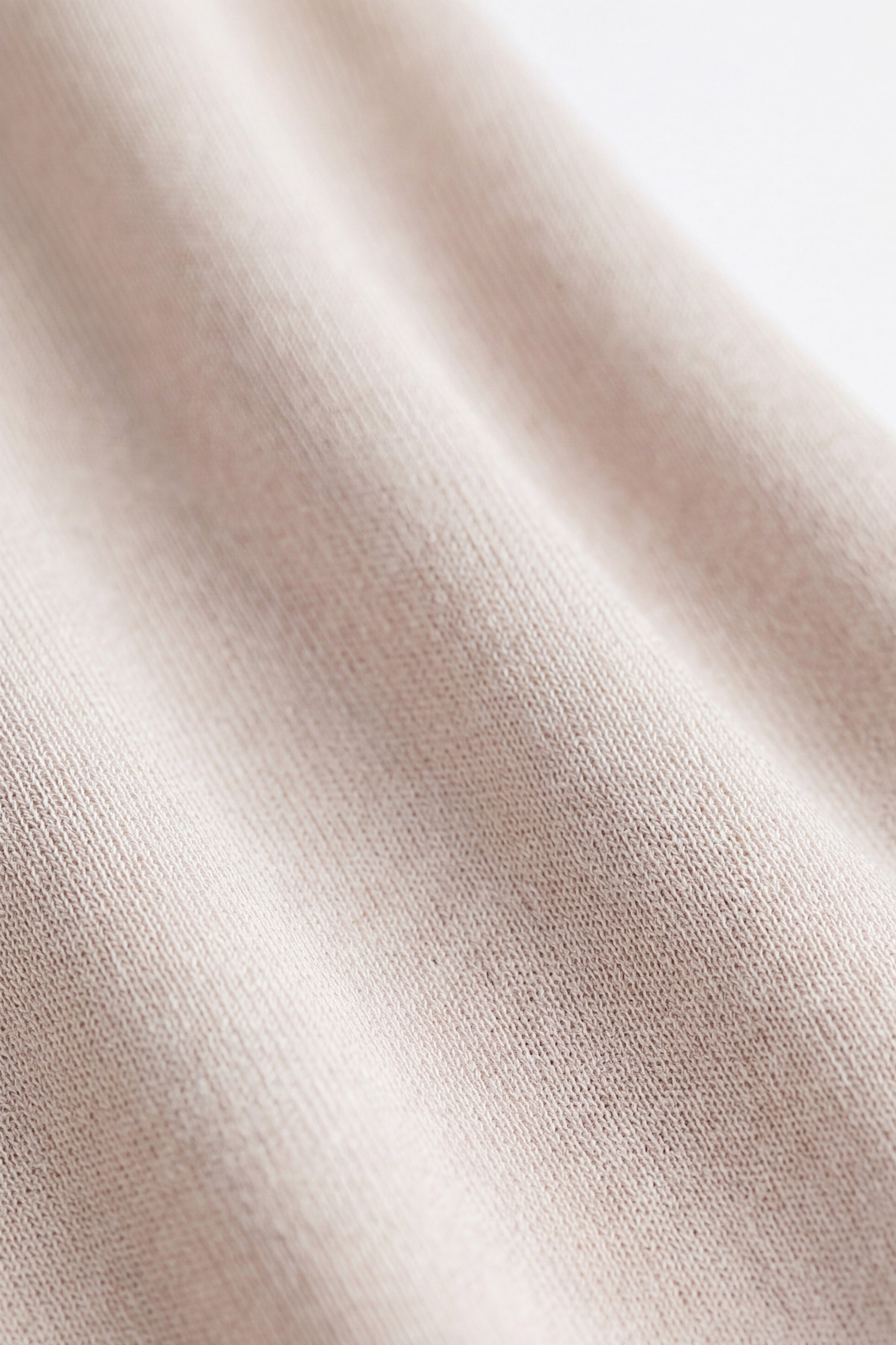 Close-up of beige fabric texture with soft, woven pattern details.