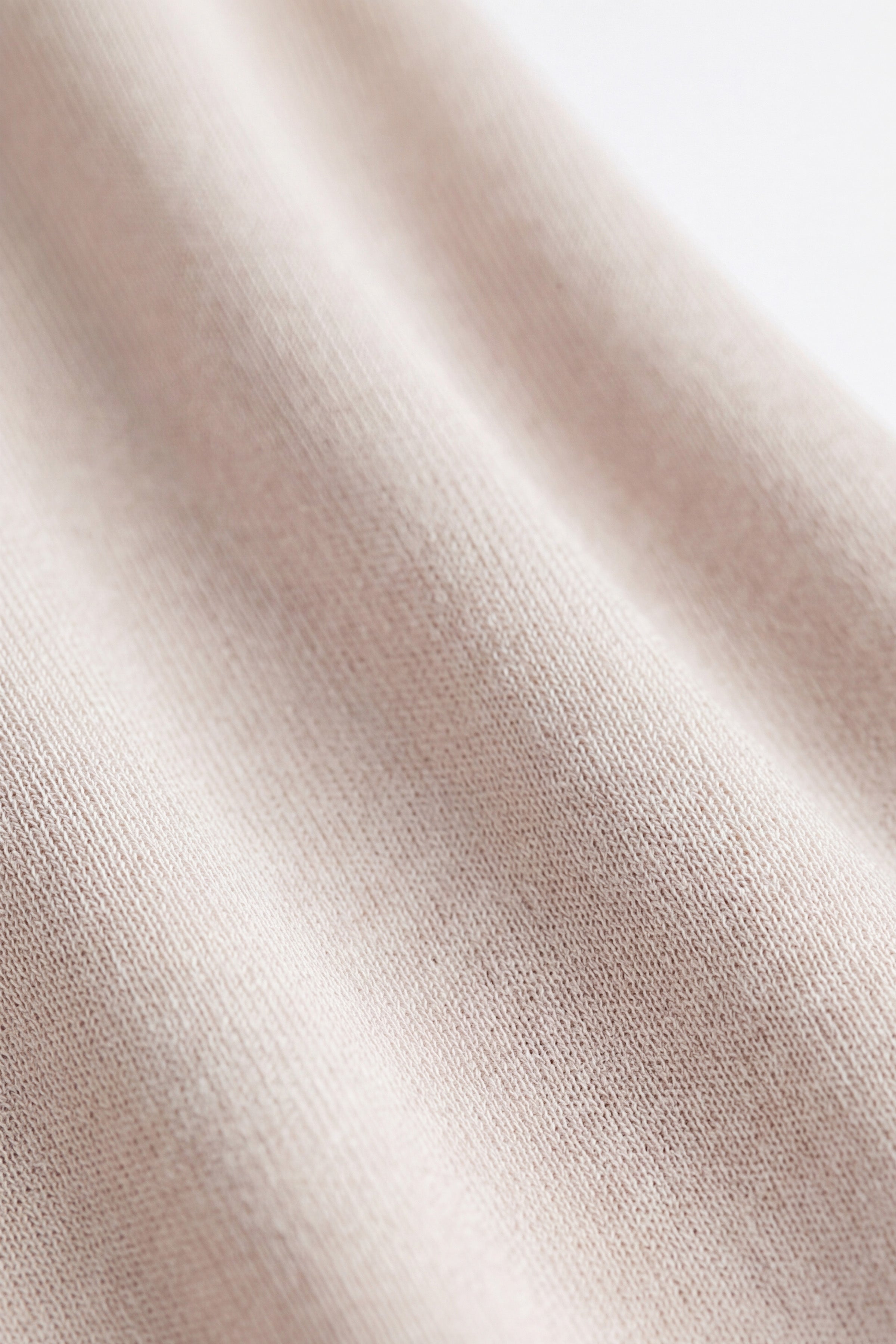 Close-up of beige fabric texture with soft, woven pattern details.