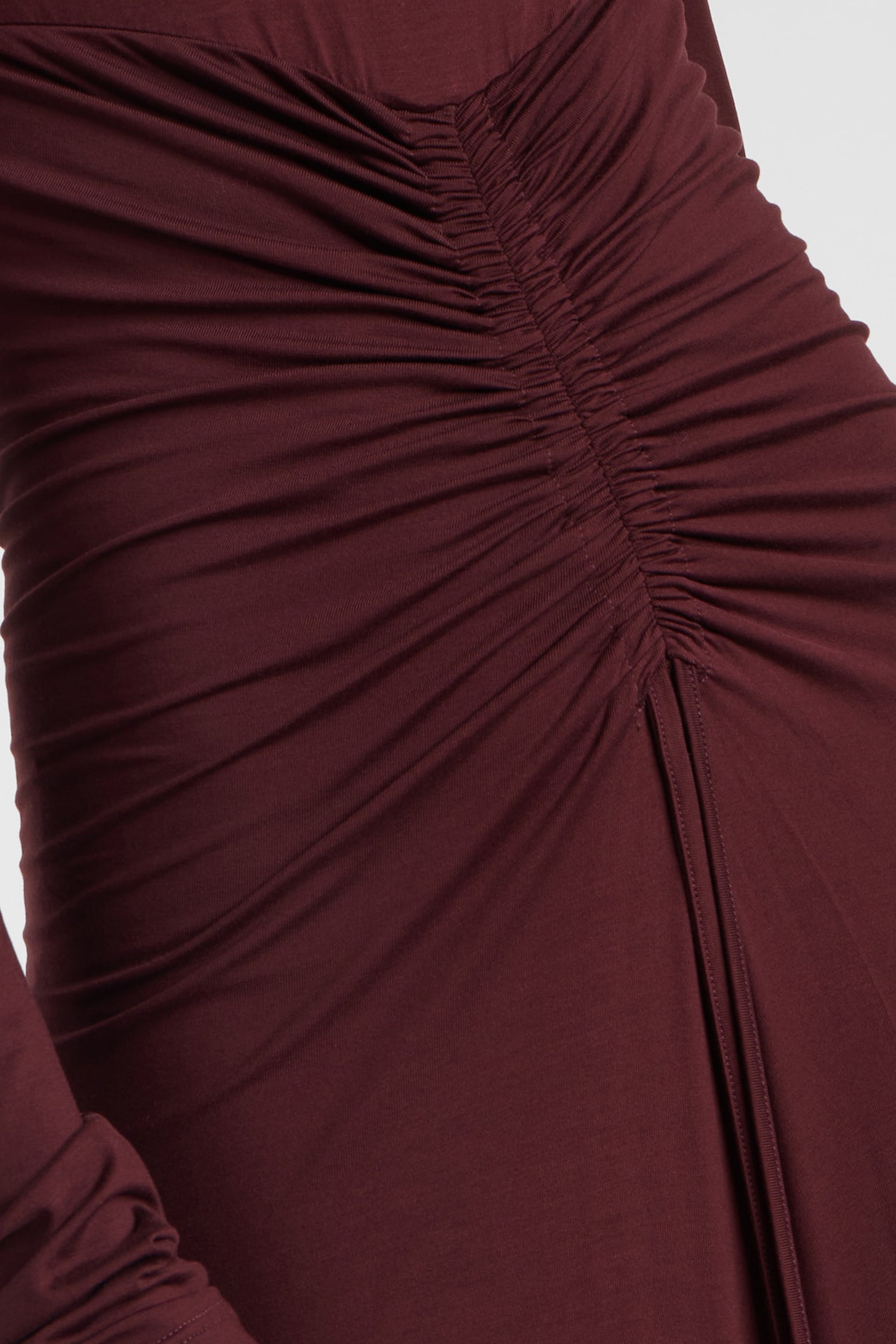 Close-up of burgundy dress with ruched detailing and long sleeves.