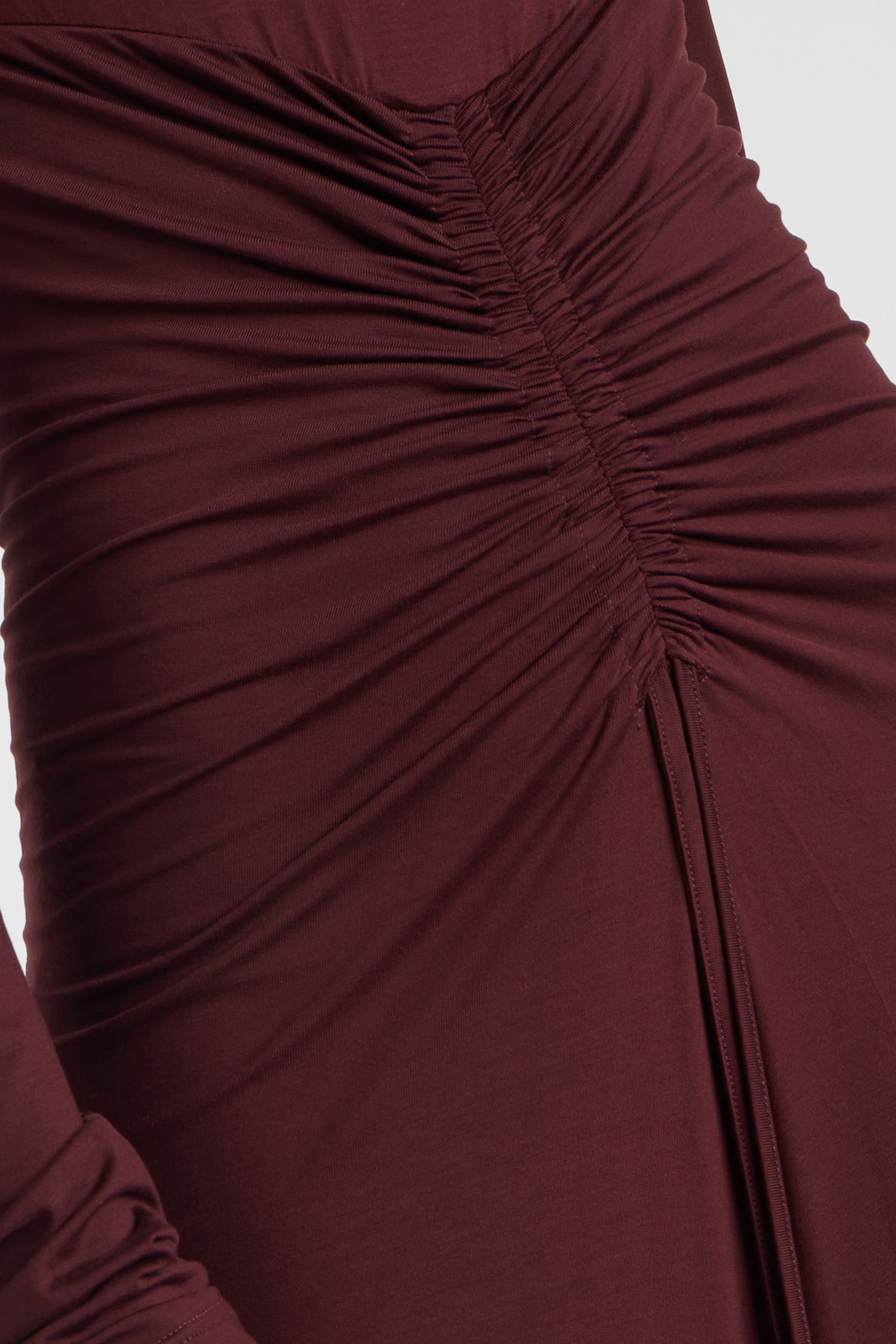 Close-up of burgundy dress with ruched detailing and long sleeves.
