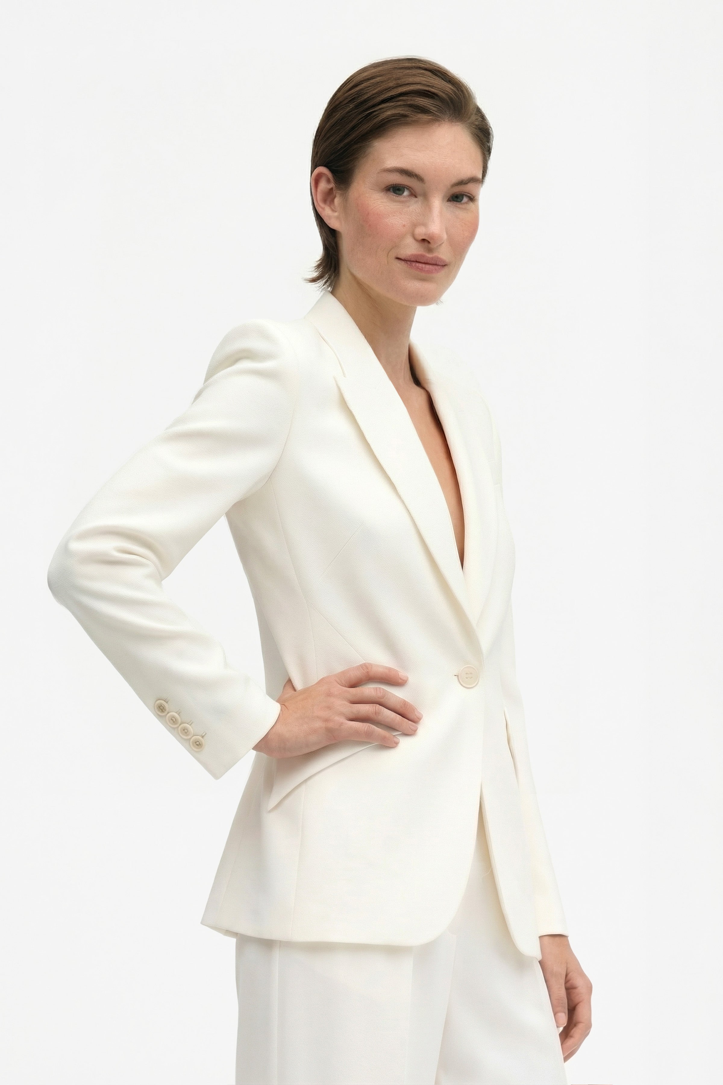 Ivory tailored blazer front view, model wearing, side pose, hands on hips.