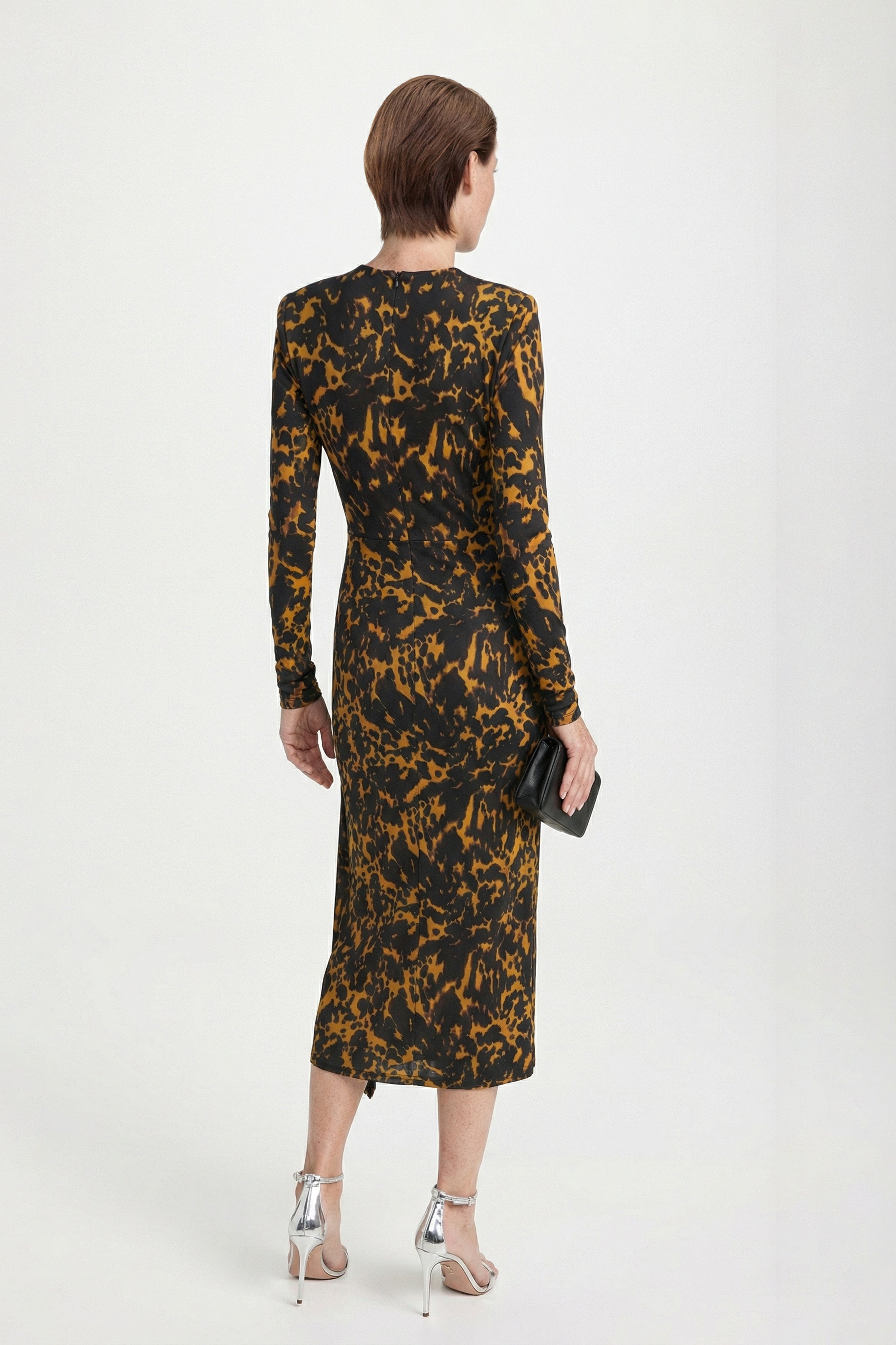 Rear view of a model in a printed long-sleeve midi dress showing a sleek tailored fit and ankle-length hemline.