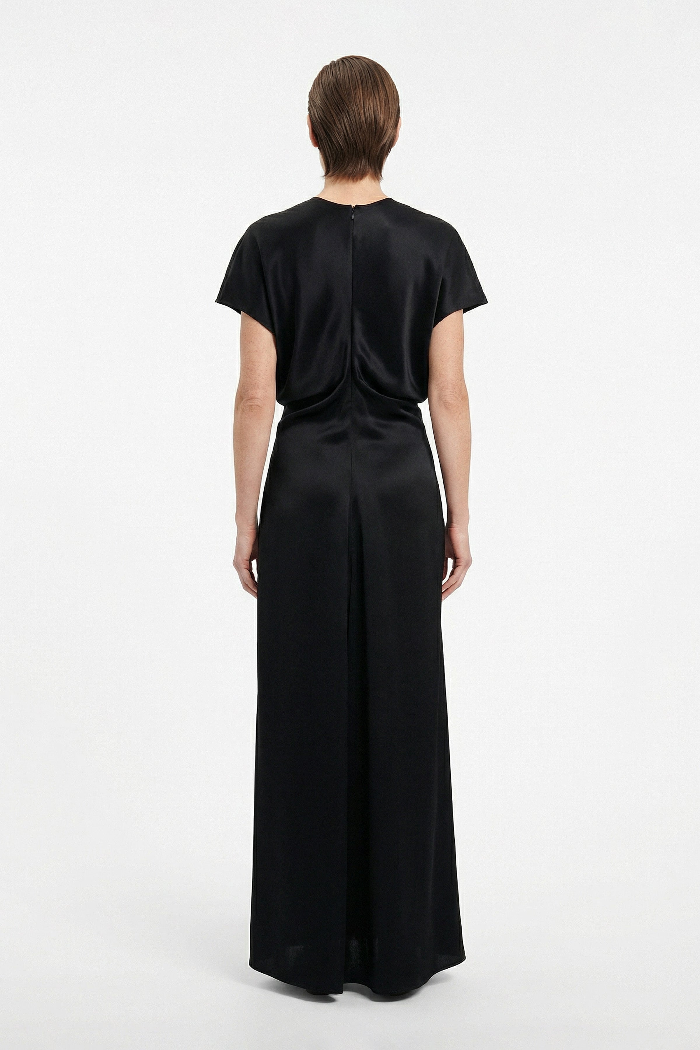 Back view of model wearing sleek black maxi dress with short sleeves.