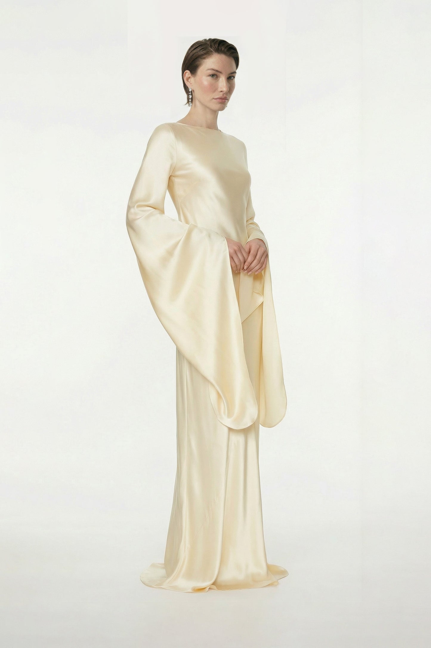 Model wearing elegant golden silk gown with flowing sleeves, front view.