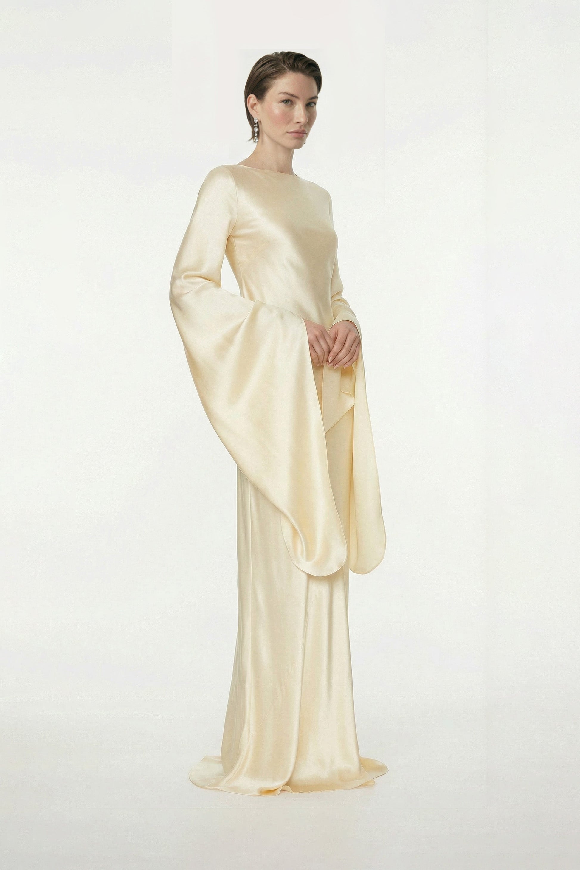Model wearing elegant golden silk gown with flowing sleeves, front view.