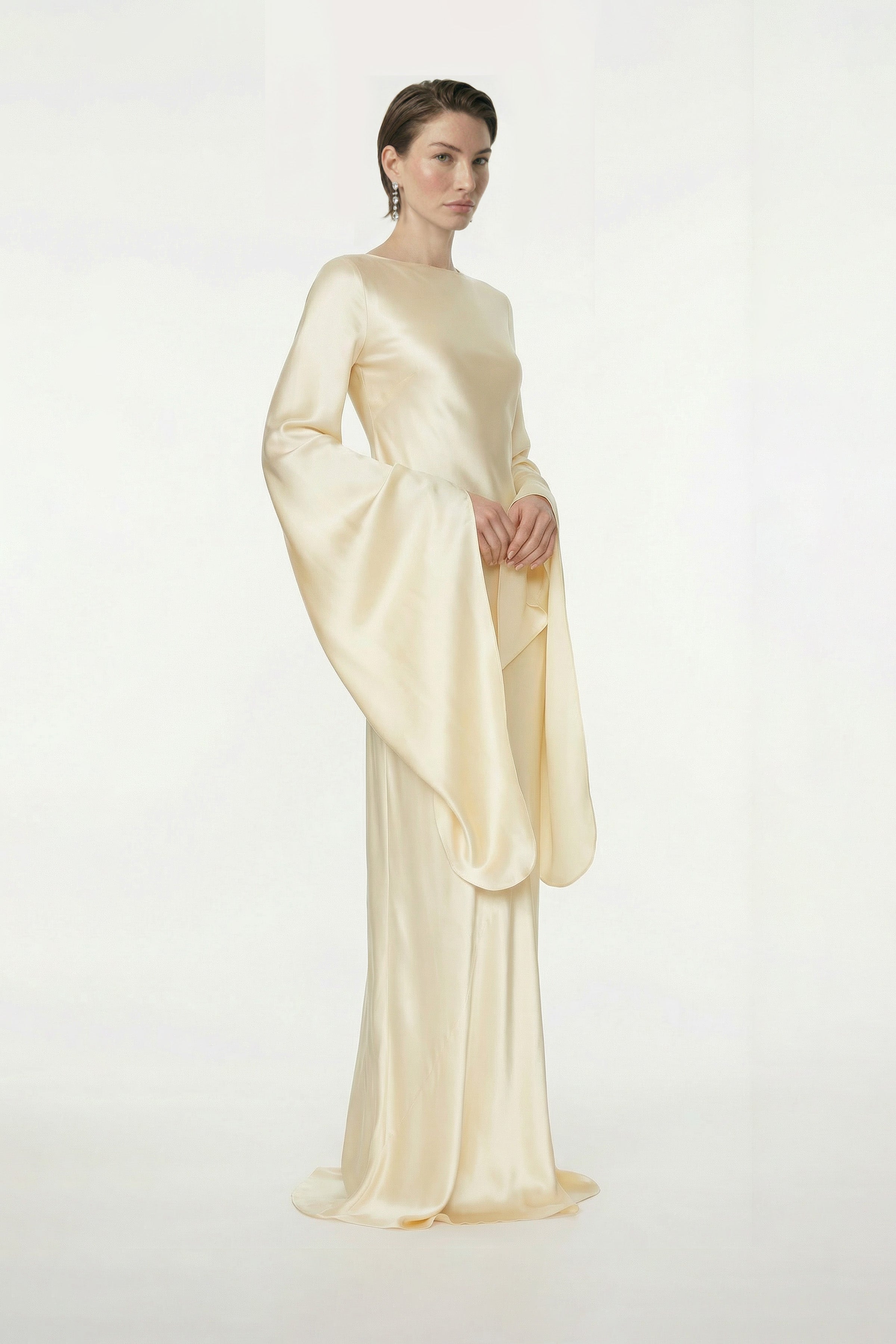 Model wearing elegant golden silk gown with flowing sleeves, front view.