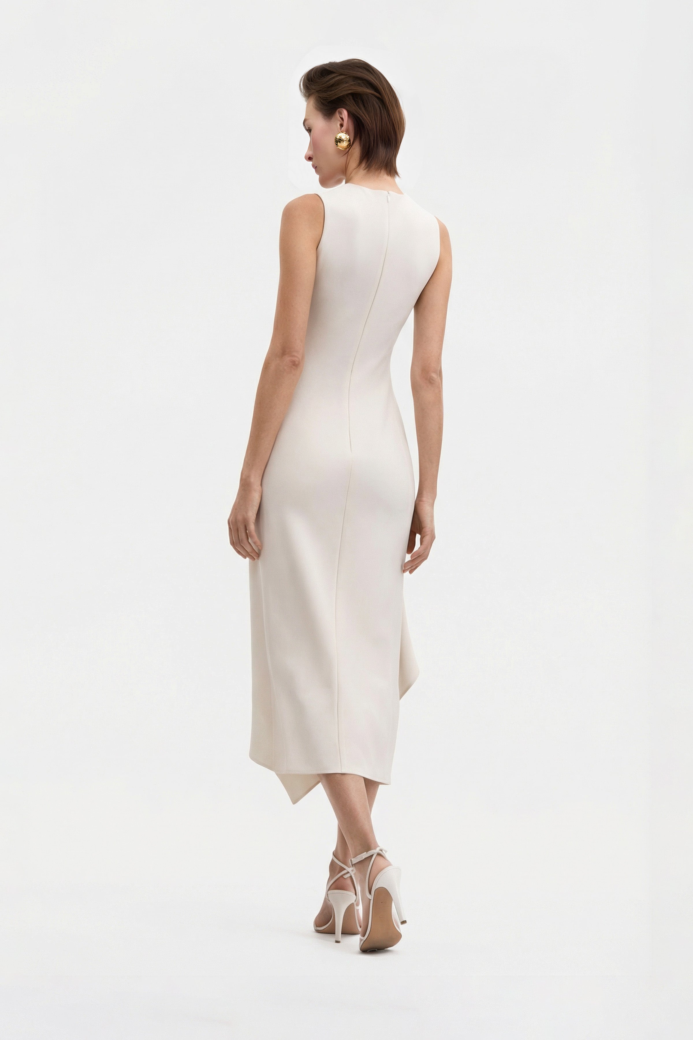 Back view of asymmetrical white dress, model walking, showcasing elegant flow and seams.