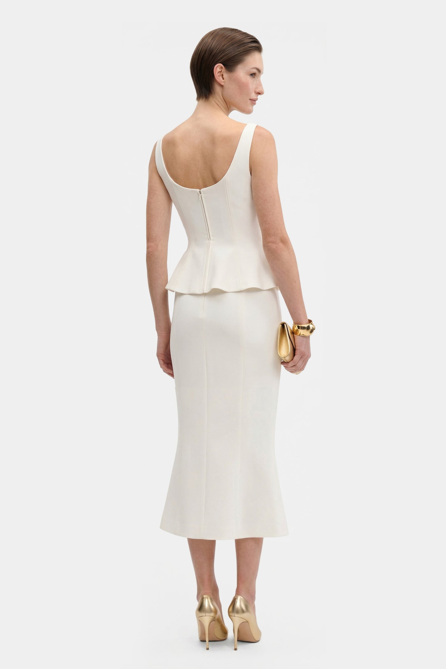 Back view of Ivory Elegance Midi skirt with peplum detail, gold accessories.