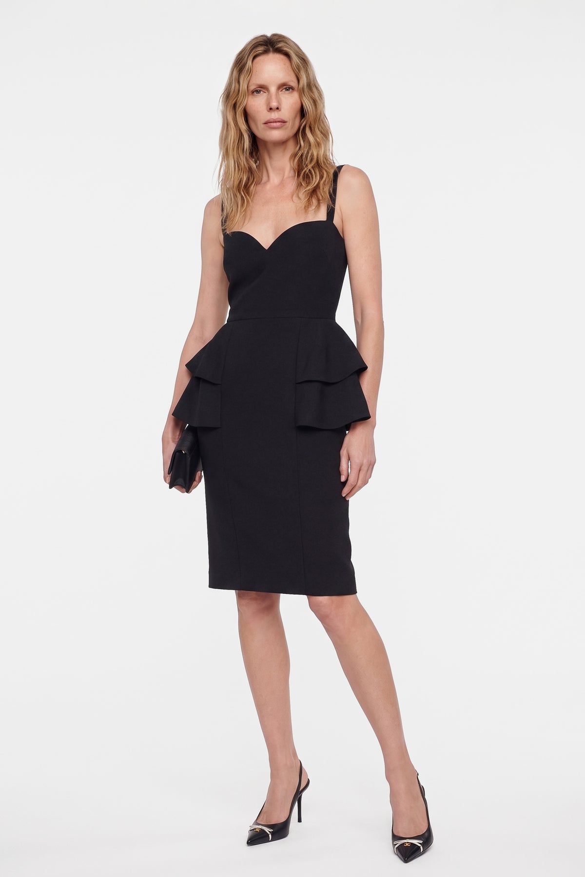 Model in black sweetheart neckline dress, front view, ruffled detail, holding clutch.