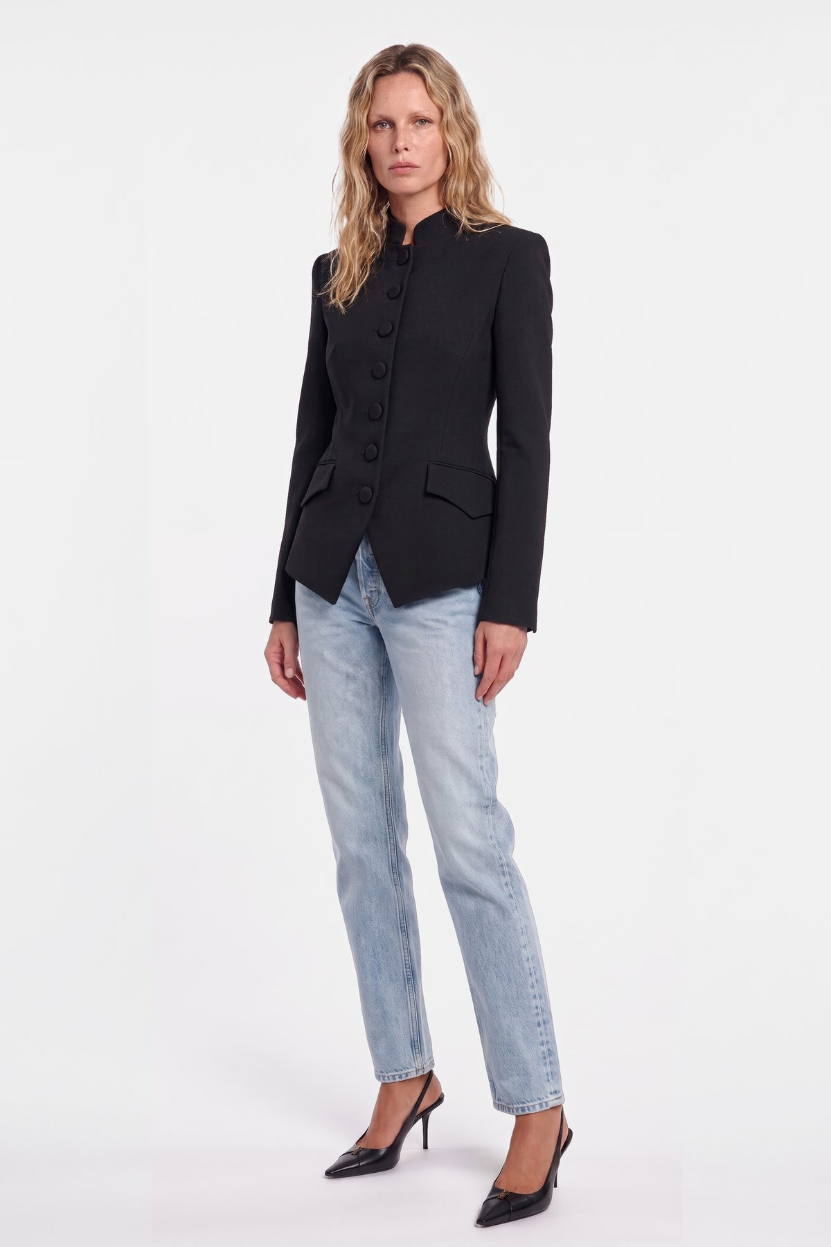 Model in structured black blazer; front view with jeans and heels.