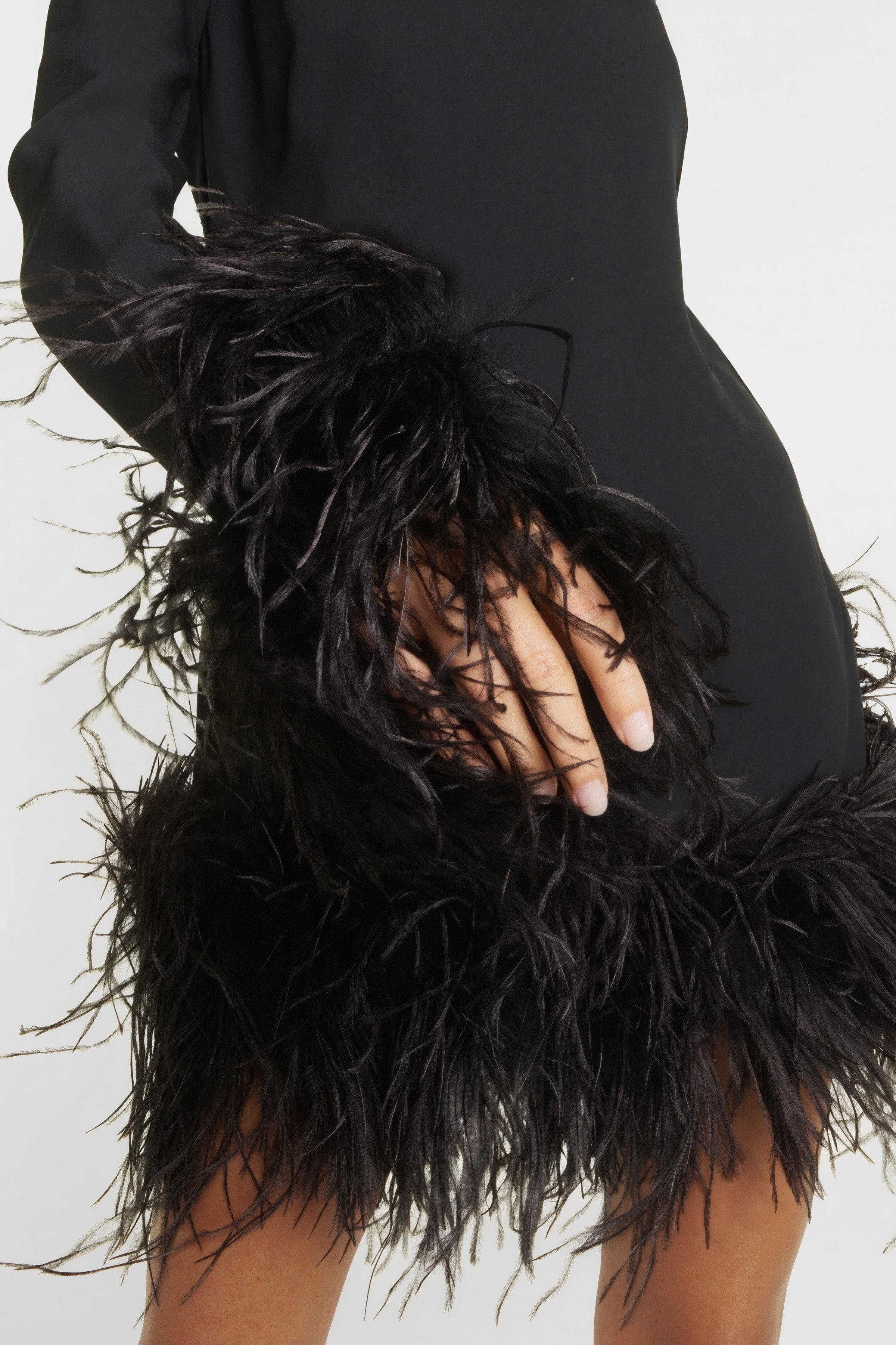 Close view of cocktail turtleneck mini dresses featuring feather detailing at the hem