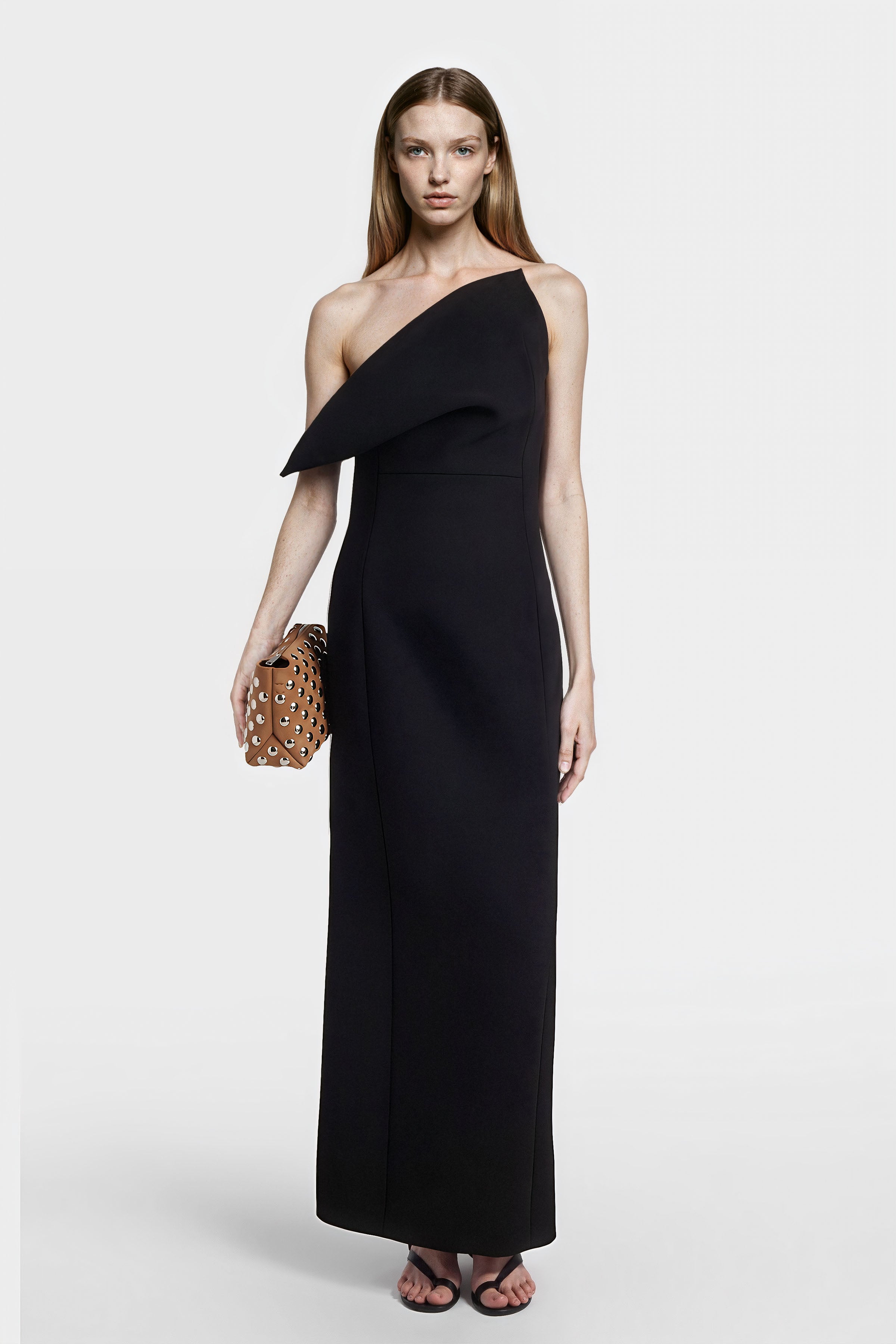 Front view of a black asymmetric one-shoulder gown showing structured drape and clean lines.