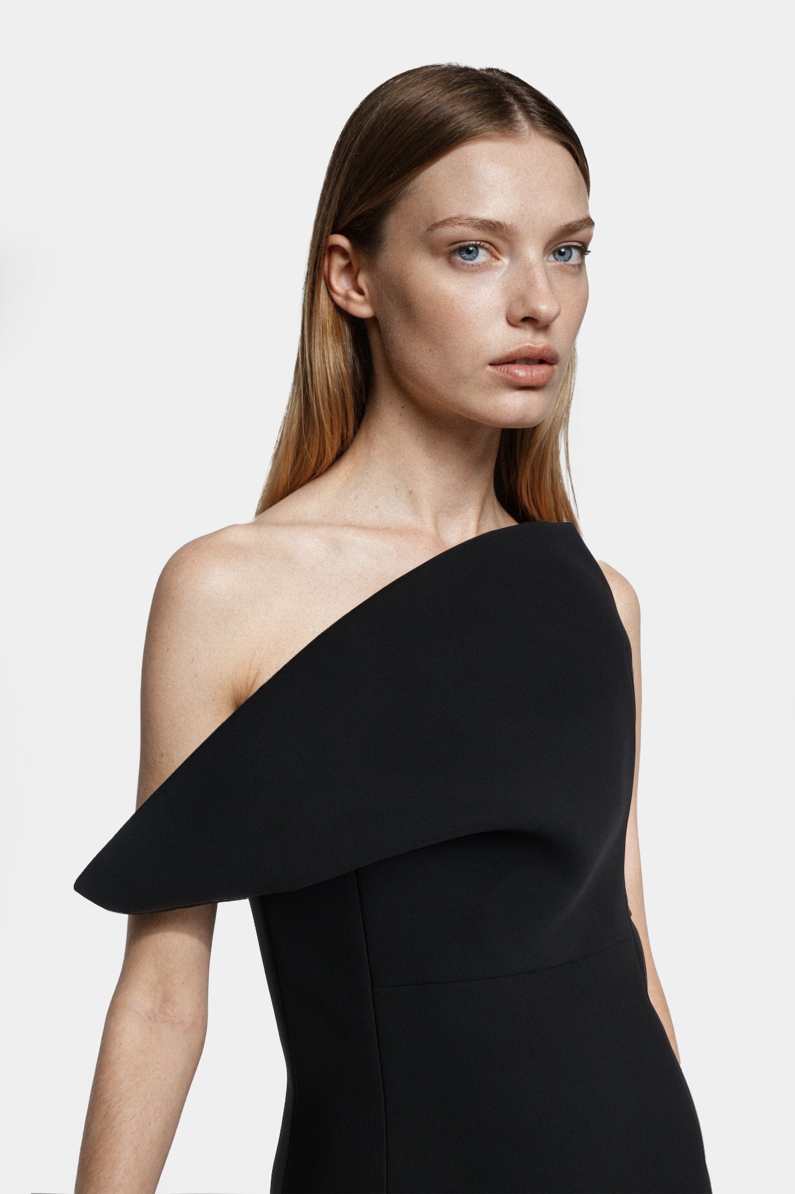 Side view of a black asymmetric one-shoulder gown showing structured drape and clean lines.
