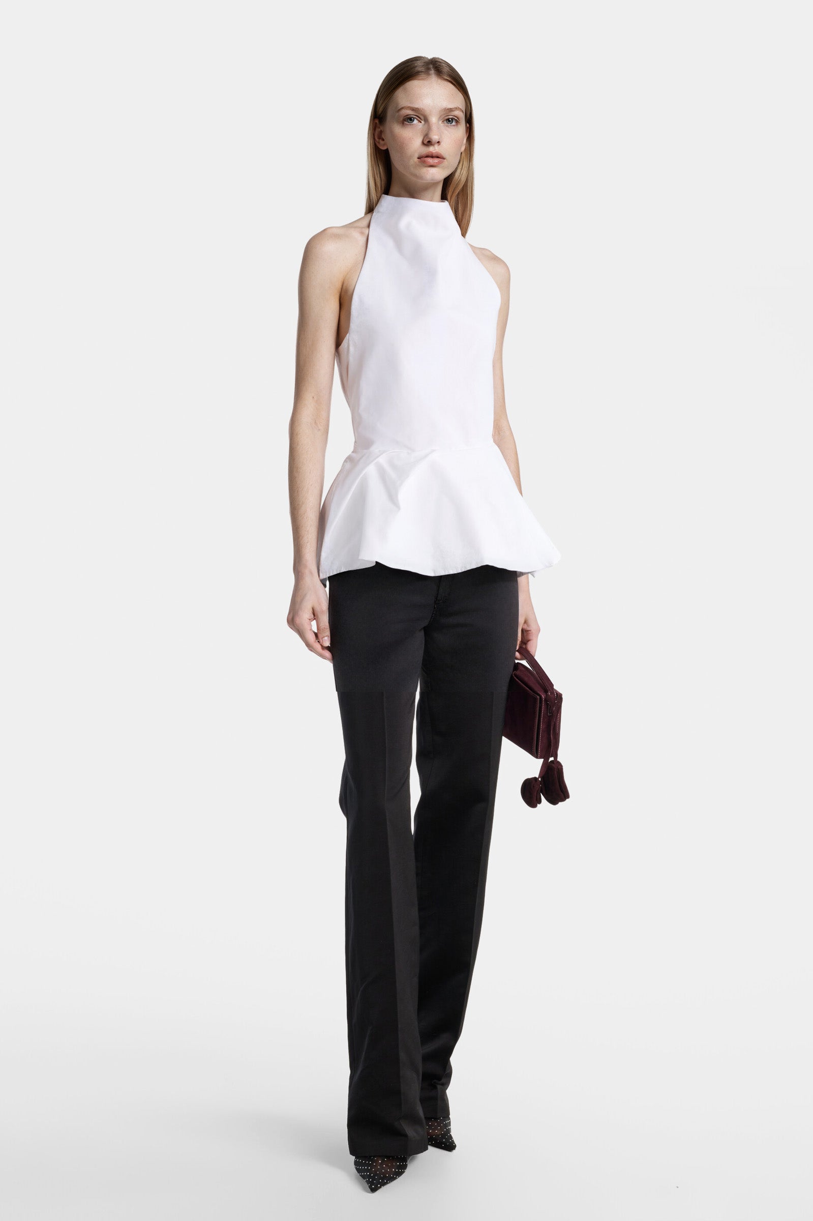 Front view of a sculptural white halter top with peplum-inspired volume.
