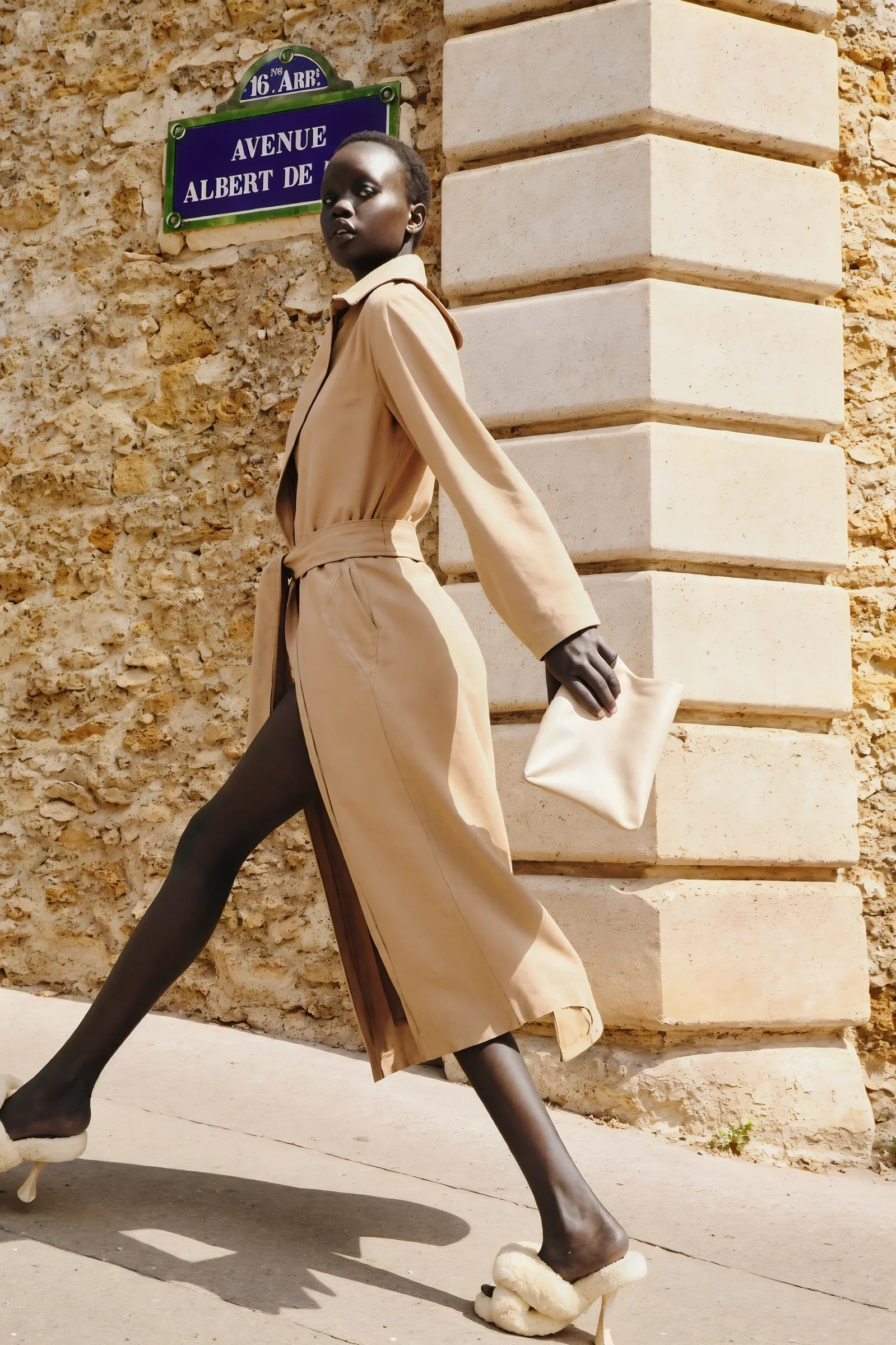 Model walking confidently in beige classic belted trench coat on city street