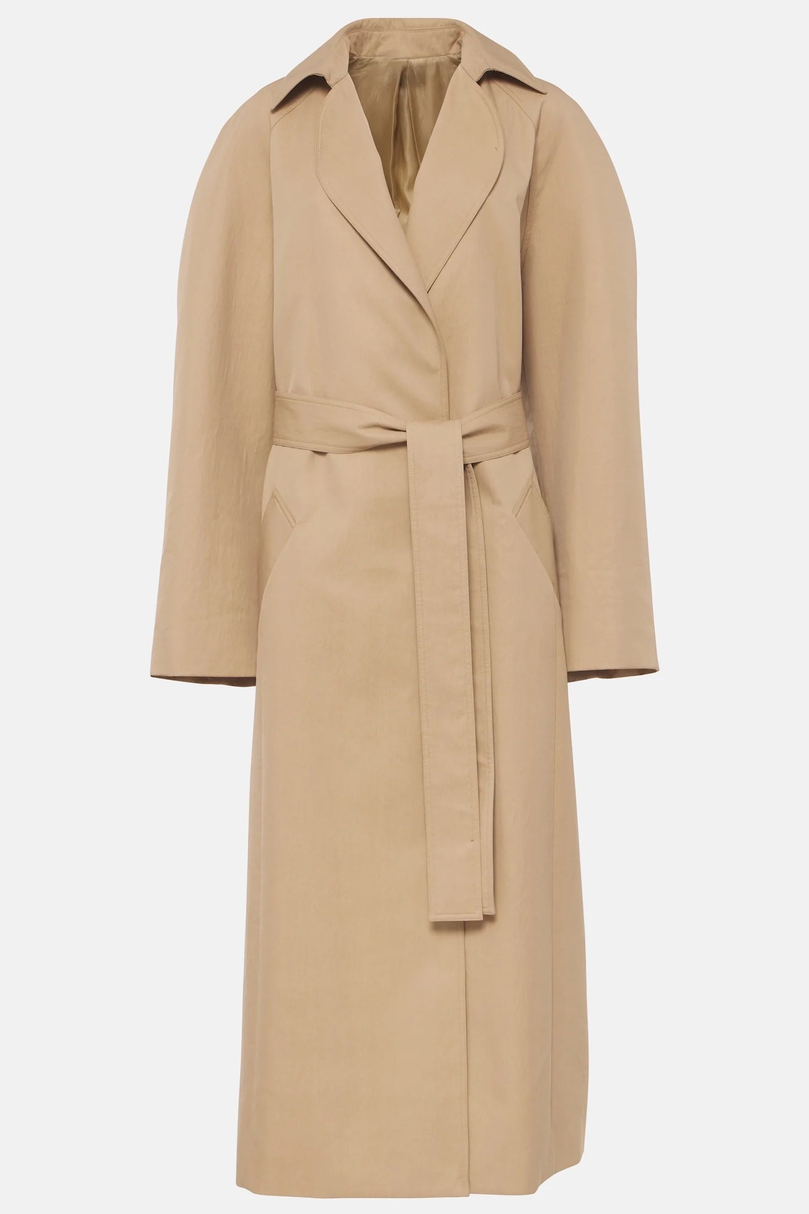 Beige belted trench coat styled with white clutch and heels outdoors
