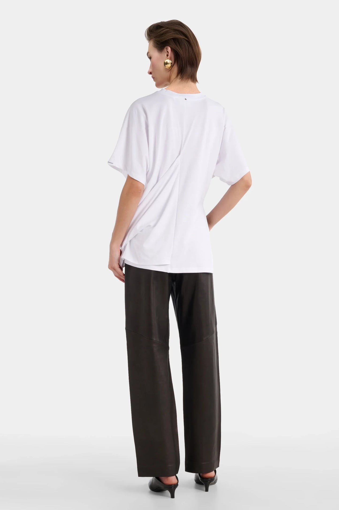 Back view of white sculptural tee with relaxed draping.
