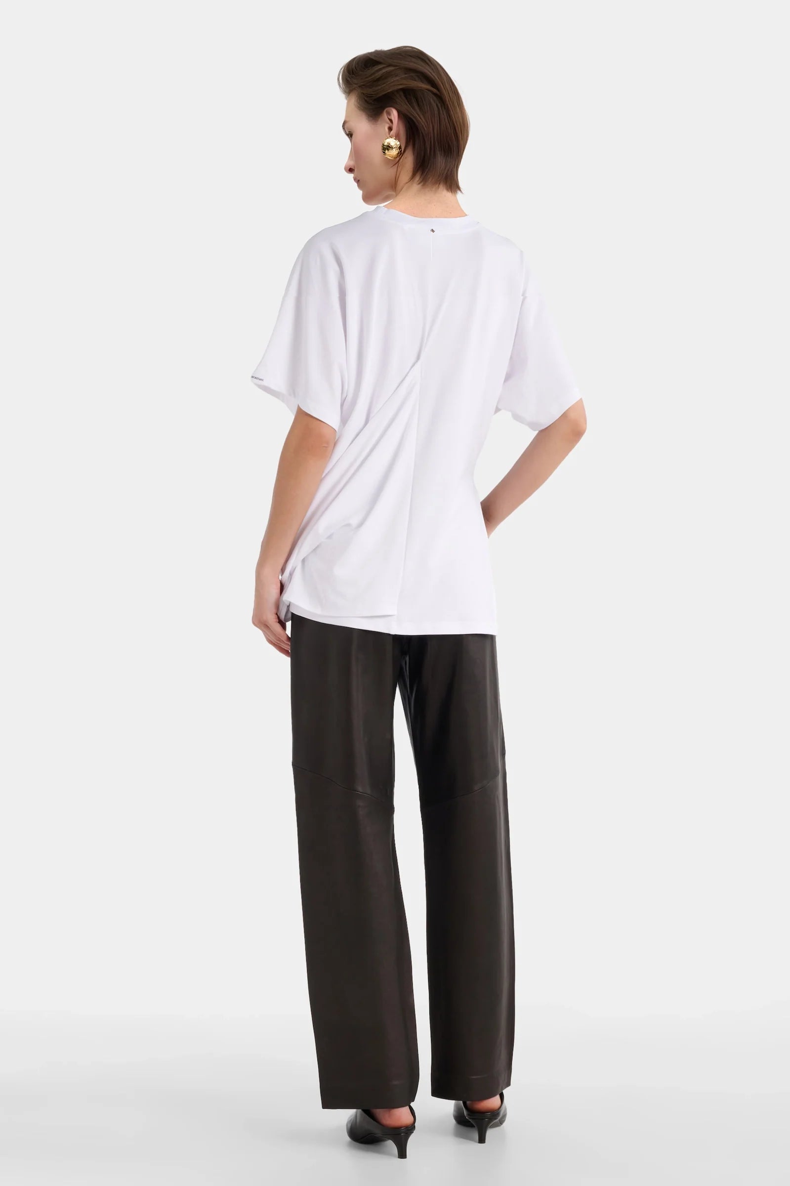 Back view of white sculptural tee with relaxed draping.