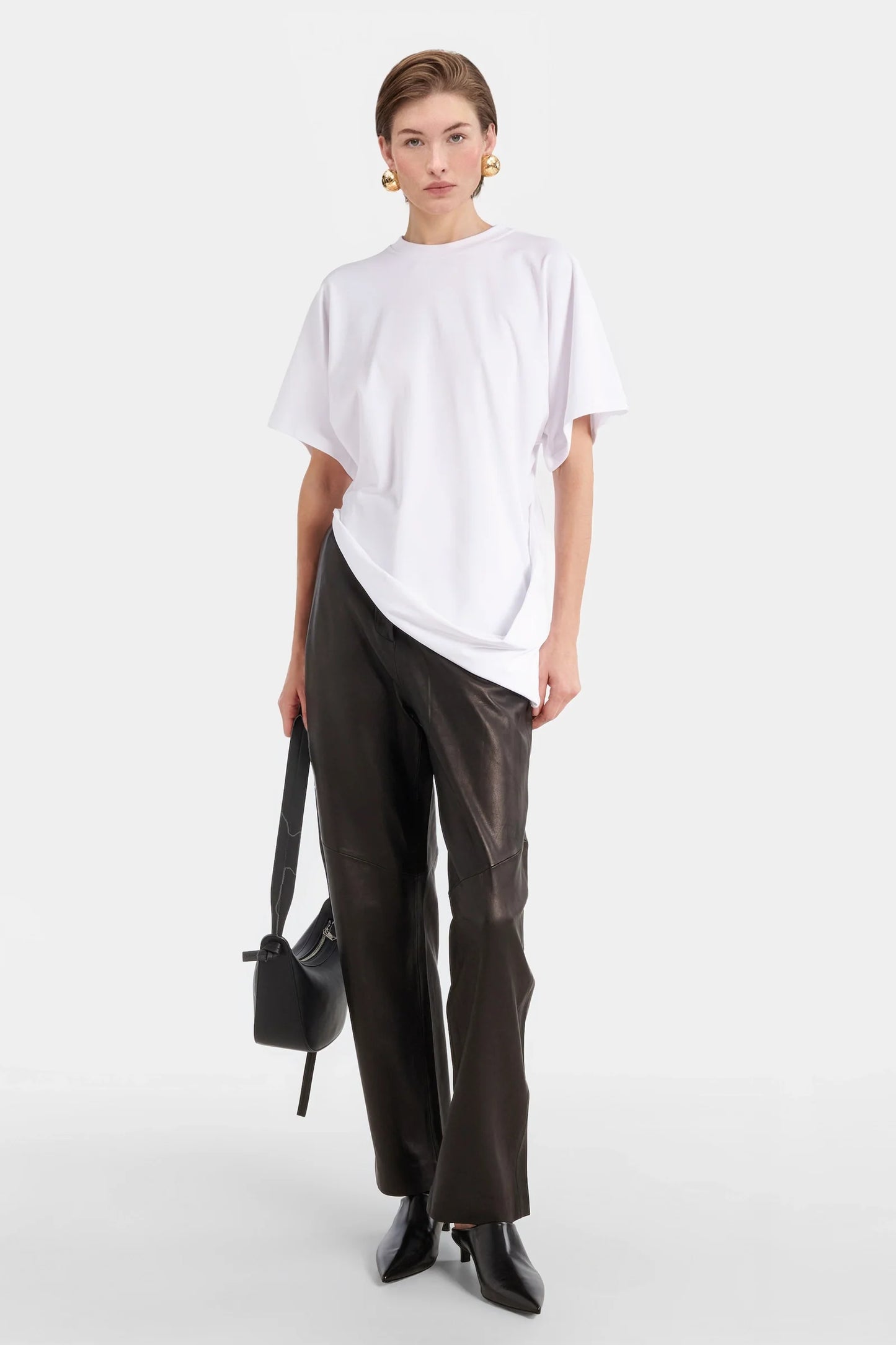 Model wearing white oversized t-shirt with draped front detail.