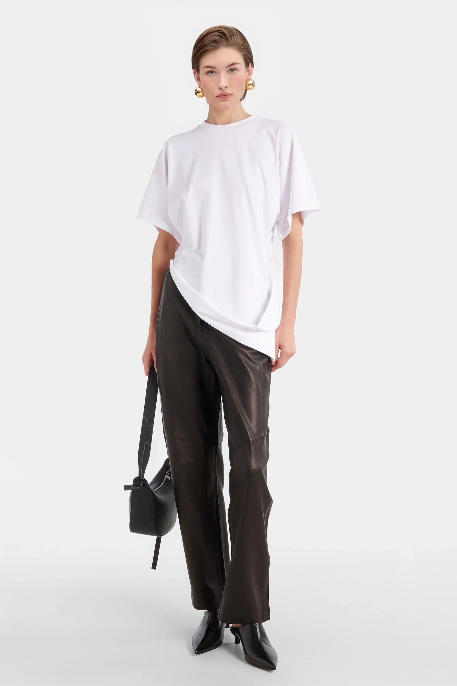 Model wearing white oversized t-shirt with draped front detail.