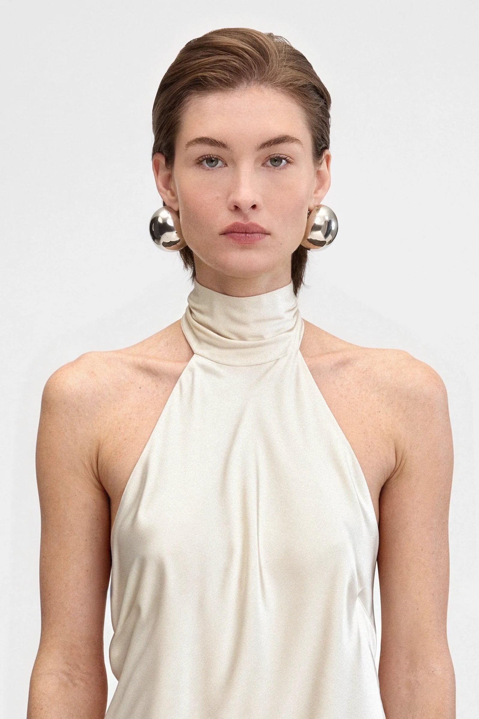 Close-up of the beige satin fabric and tied neckline of the halter dress.