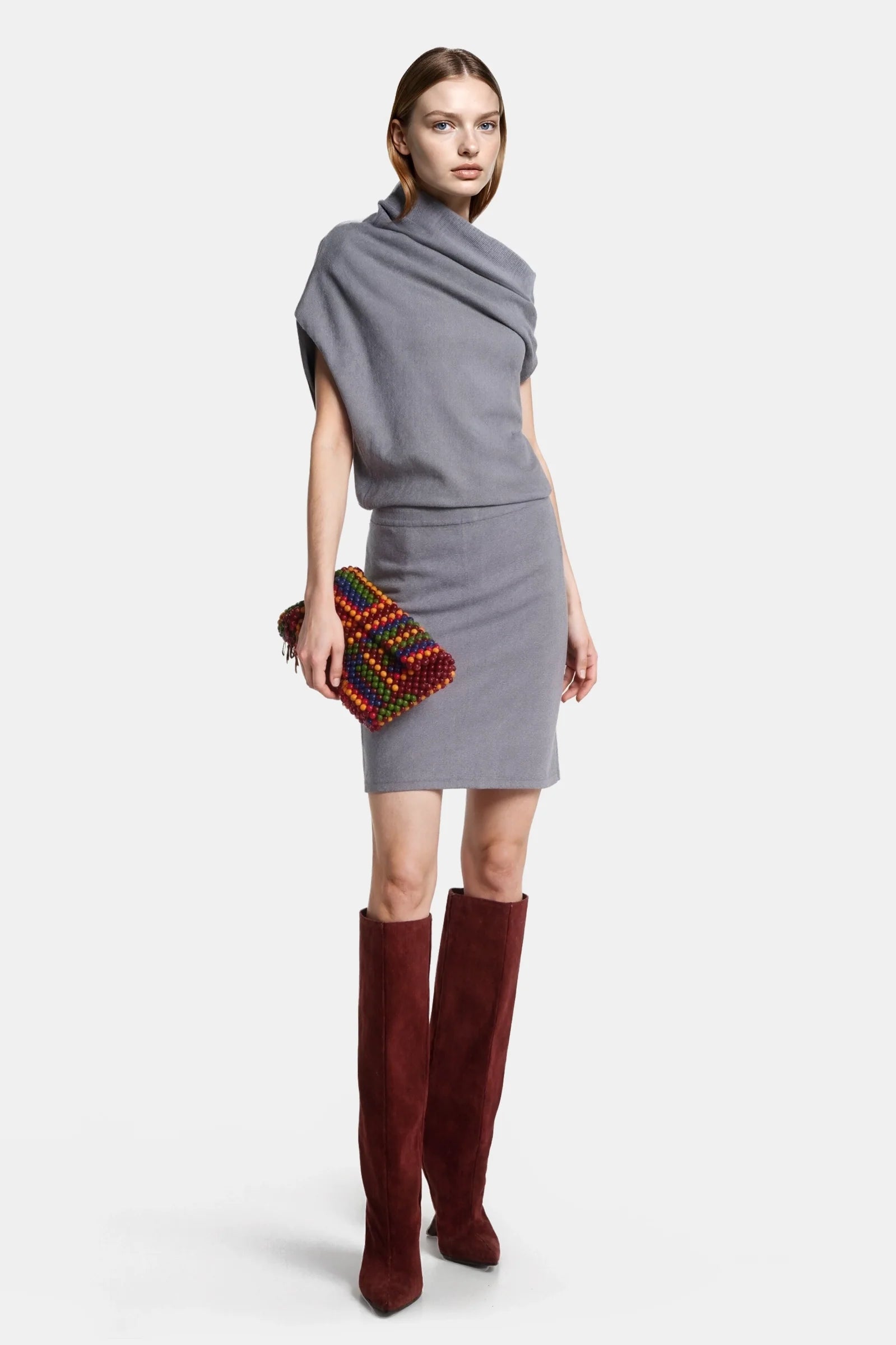Asymmetric knit grey mini dress styled with boots and clutch