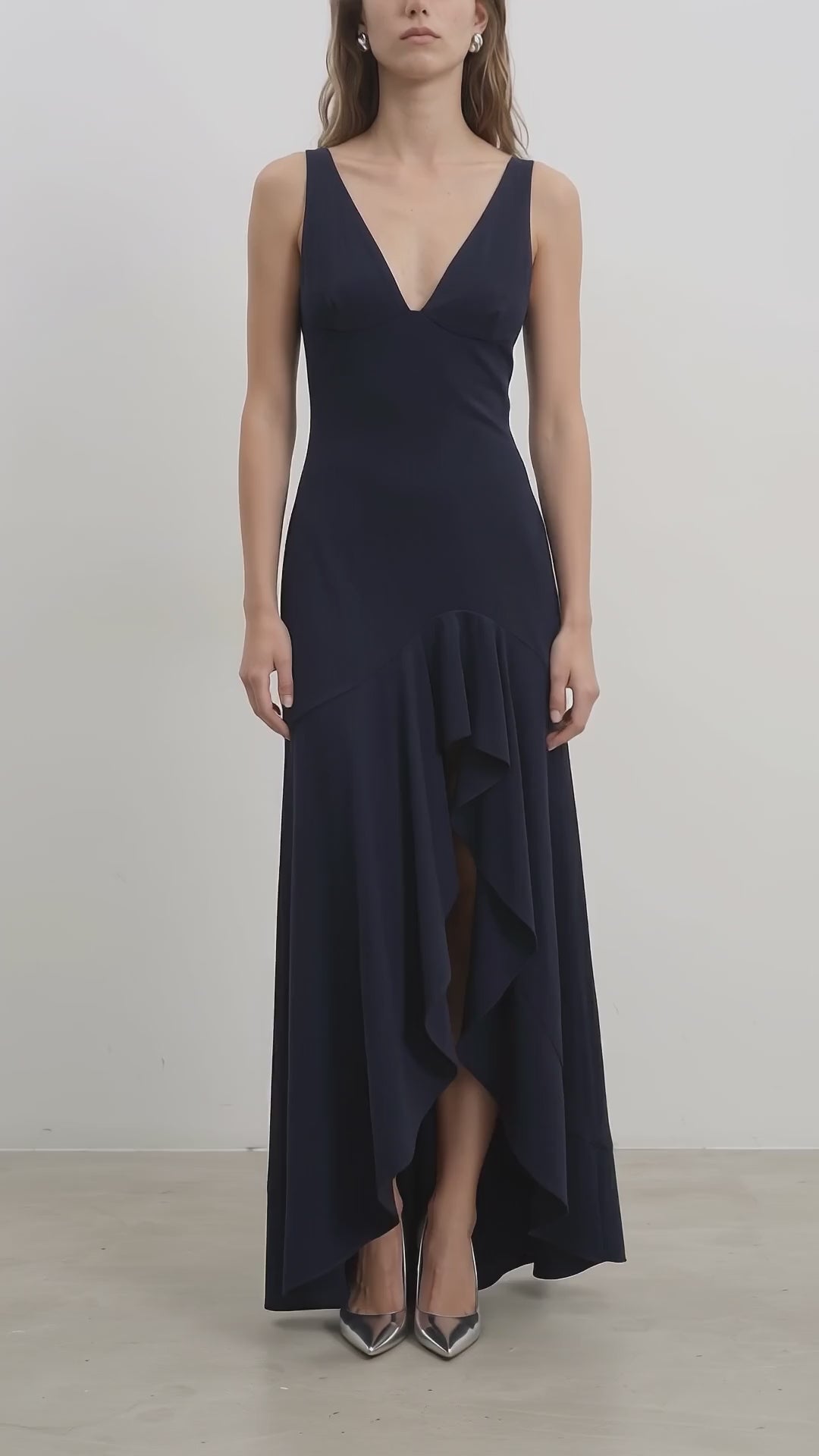 Navy ruffle hem gown video, front and back view, V-neckline, asymmetrical ruffle hem, model showcasing movement and fit.