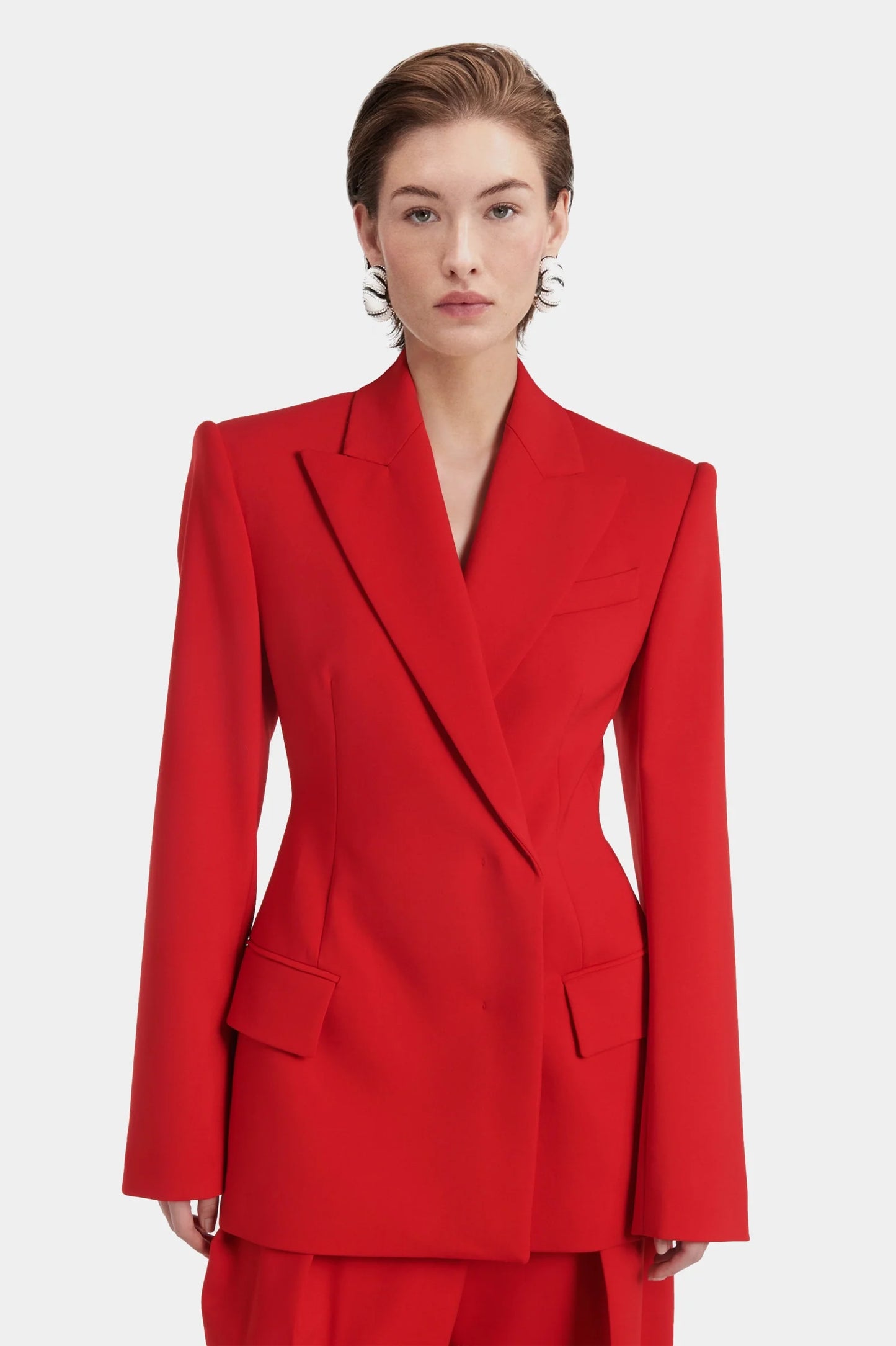 Close-up of red blazer showing lapel, flap pockets, and buttoned cuffs.