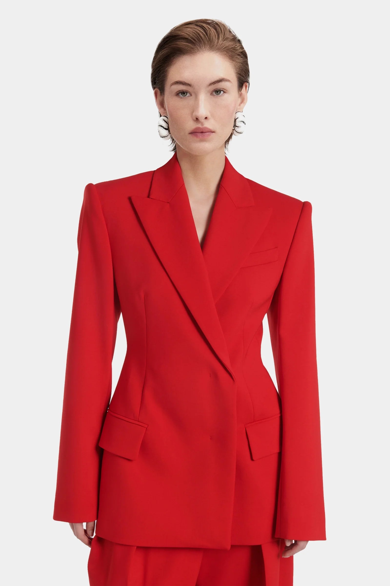Close-up of red blazer showing lapel, flap pockets, and buttoned cuffs.