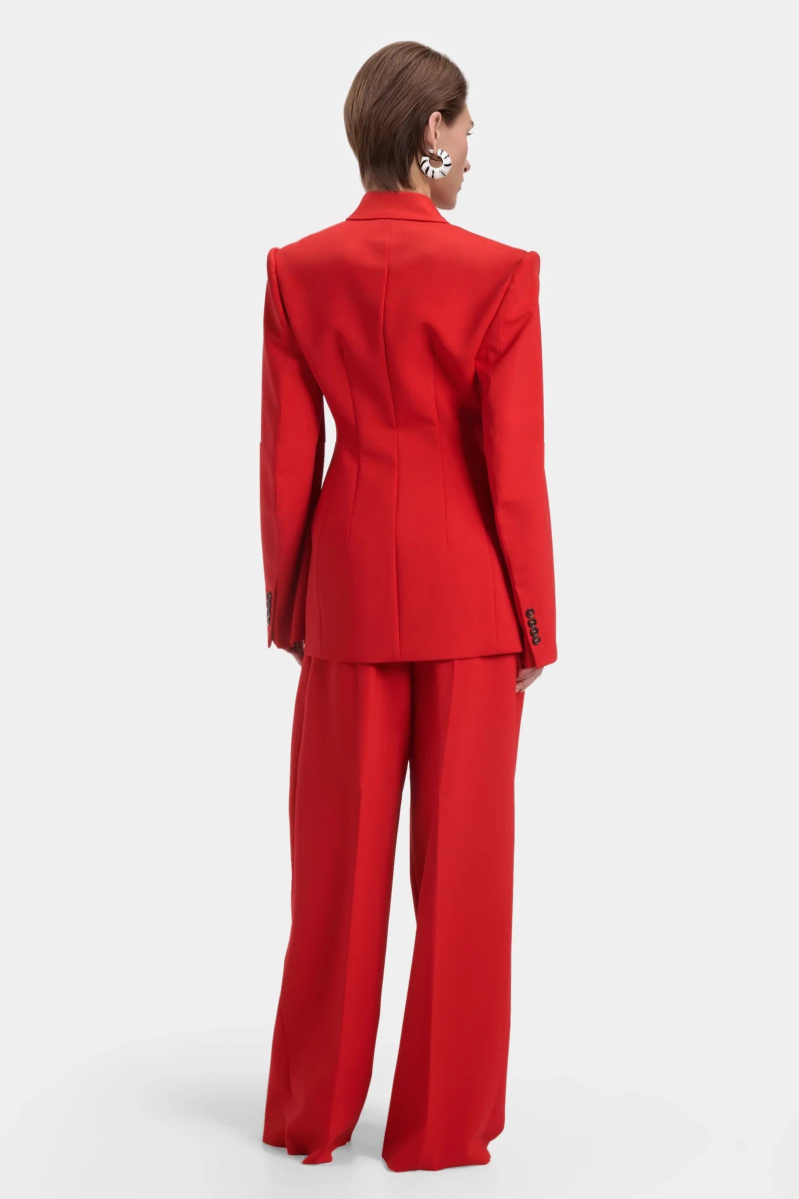 Back view of structured red blazer with defined seams and sharp tailoring.